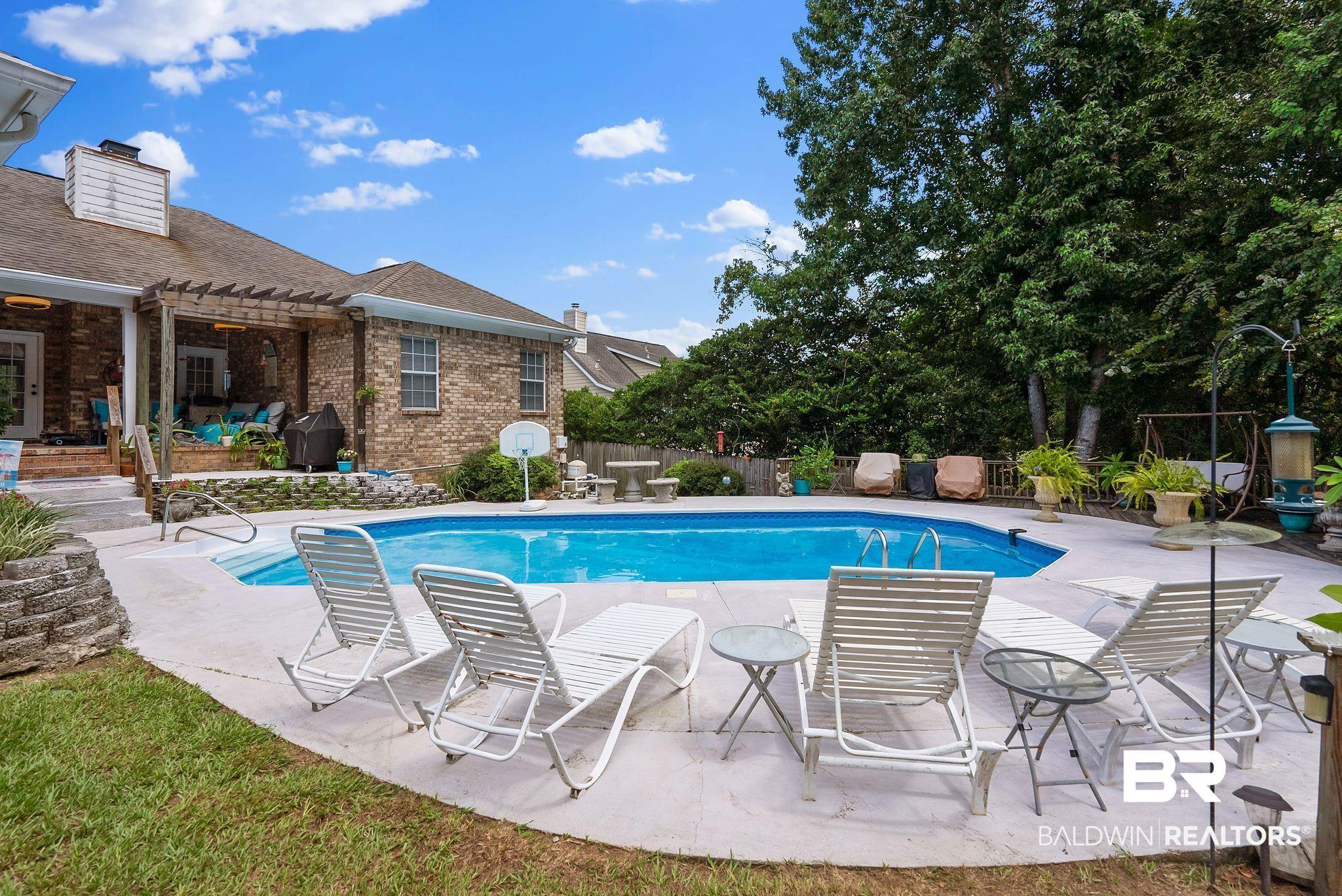Image 2: Brick exterior home featuring a swimming pool with concrete surround