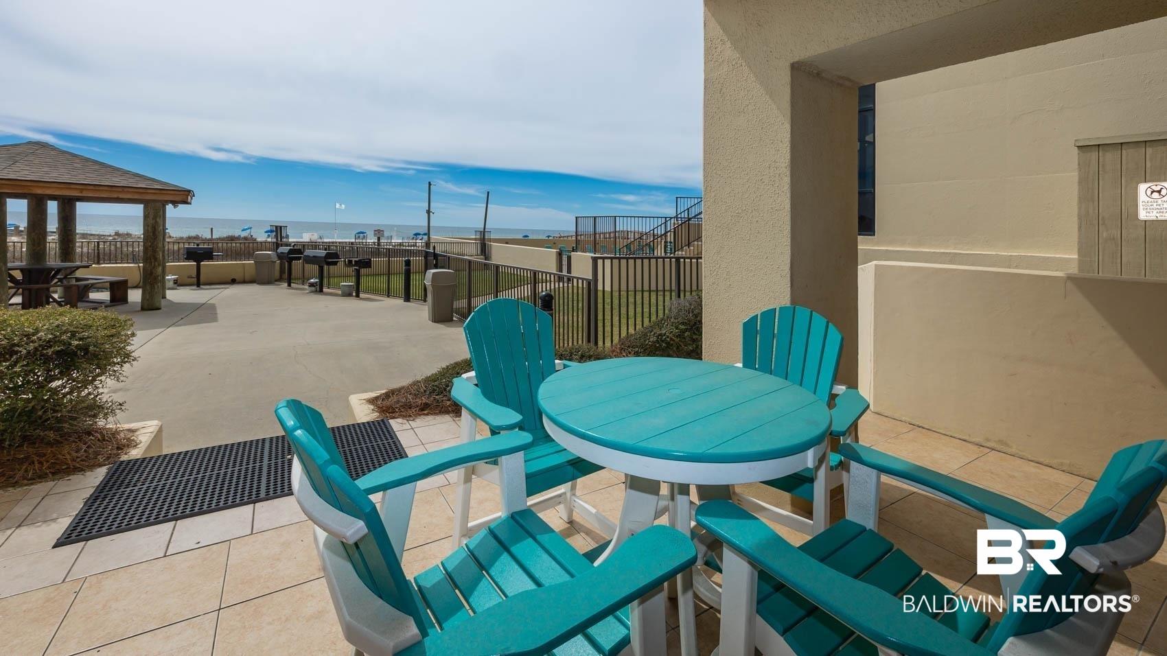 Image 4: Outdoor patio with tile flooring, offering direct access to an expansive concrete common area