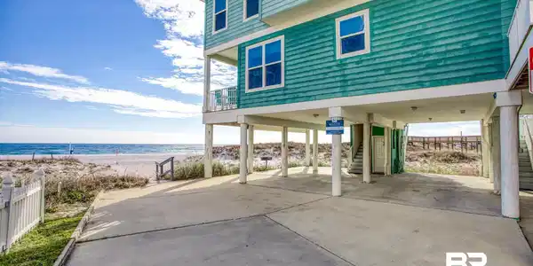 Image 3: View of patio / terrace featuring a carport, concrete driveway, stairs, a view of the beach, and a deck with water view