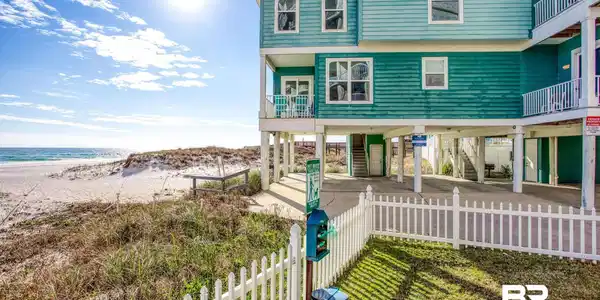 Image 4: Coastal home with a carport, view of water and beach, a balcony, stairs, and a patio