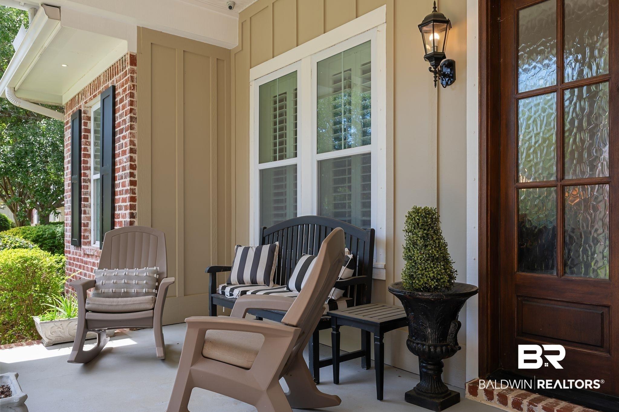 Image 3: Covered front porch featuring brick and siding construction, a panel-style wood entry door with textured glass, and a wall-mounted exterior light fixture