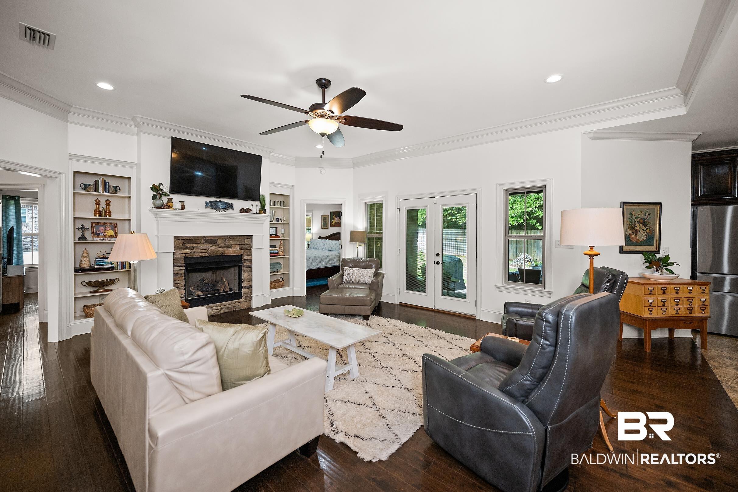 Image 2: Spacious living area featuring dark wood-finish flooring and white crown molding
