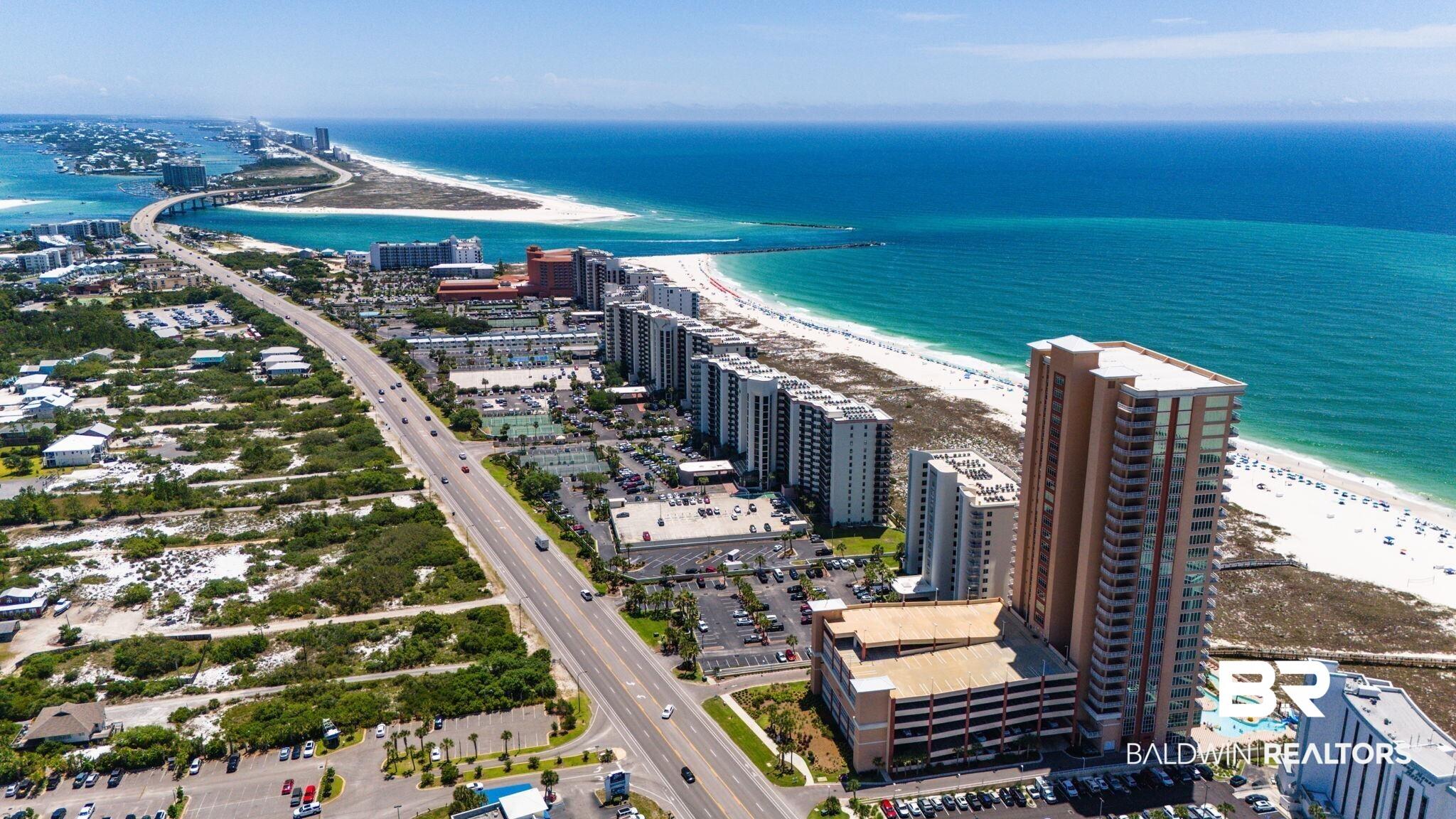 Image 2: High-rise coastal property featuring a multi-story parking garage, direct beach access, and a resort-style pool