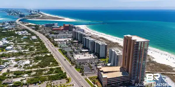 Image 2: High-rise coastal property featuring a multi-story parking garage, direct beach access, and a resort-style pool