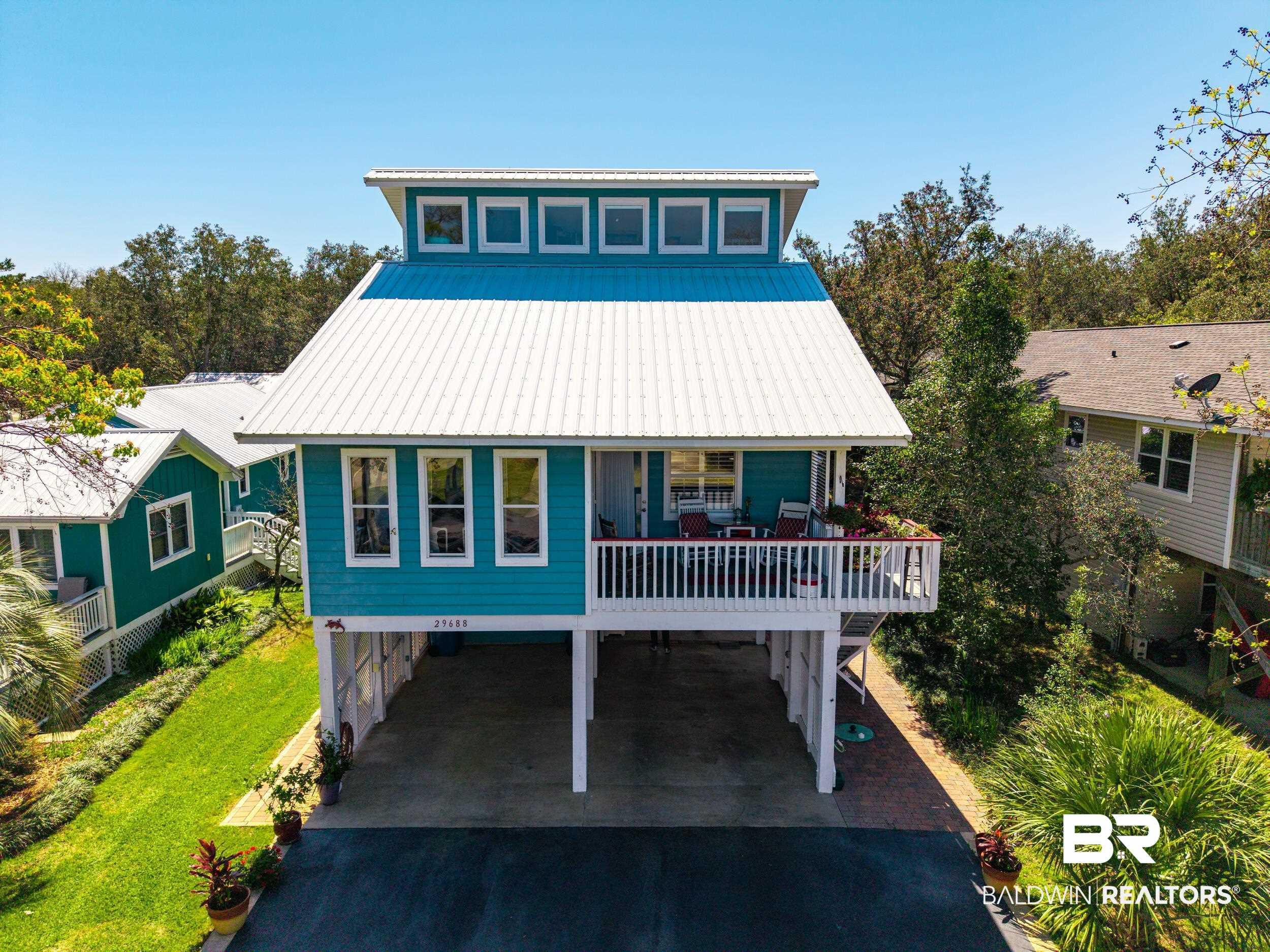 Image 2: Beach home featuring a carport, a deck, a metal roof, a patio, and driveway