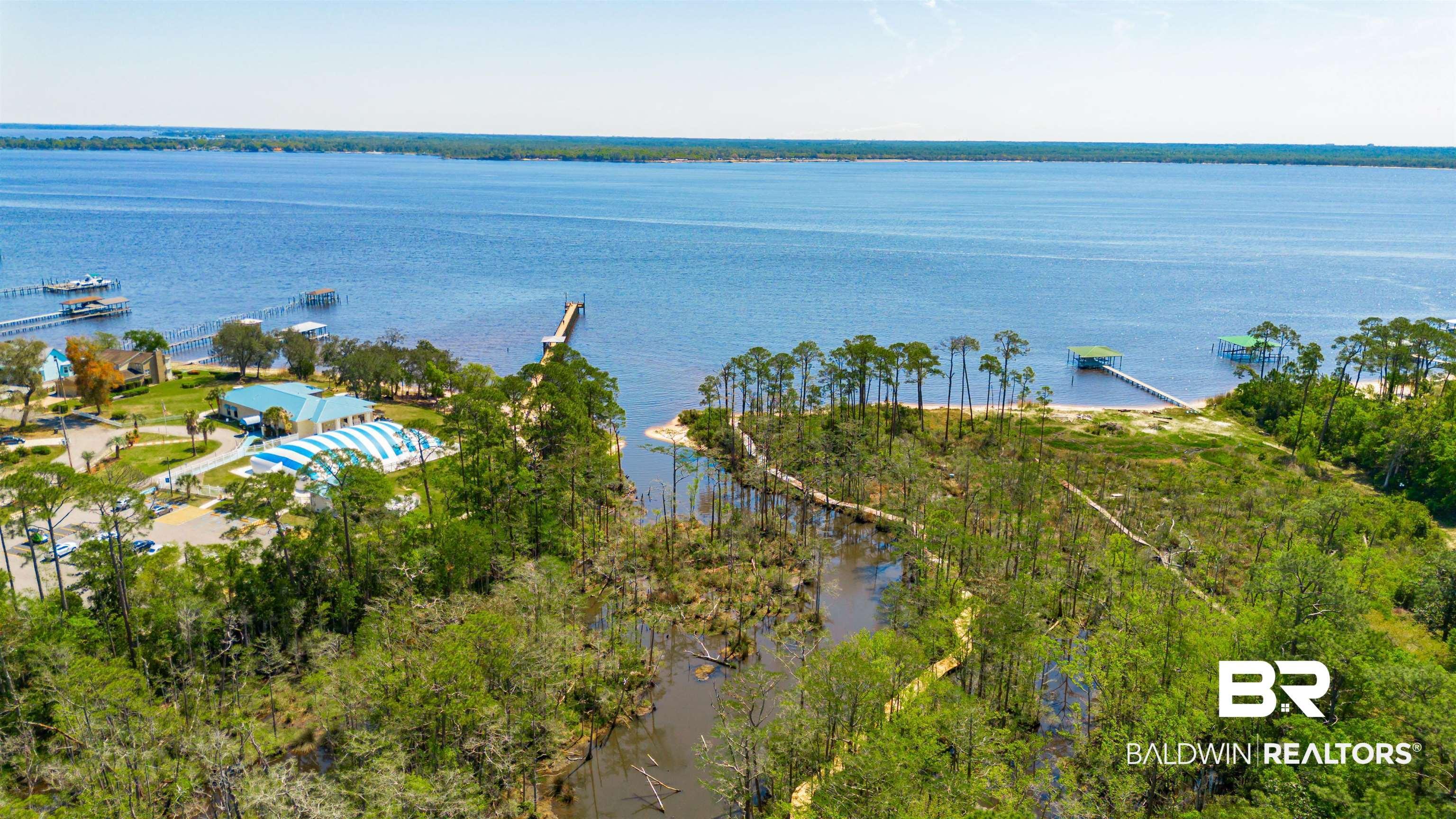Image 2: Expansive waterfront property featuring a wide body of water, multiple private docks, and a sandy beach area