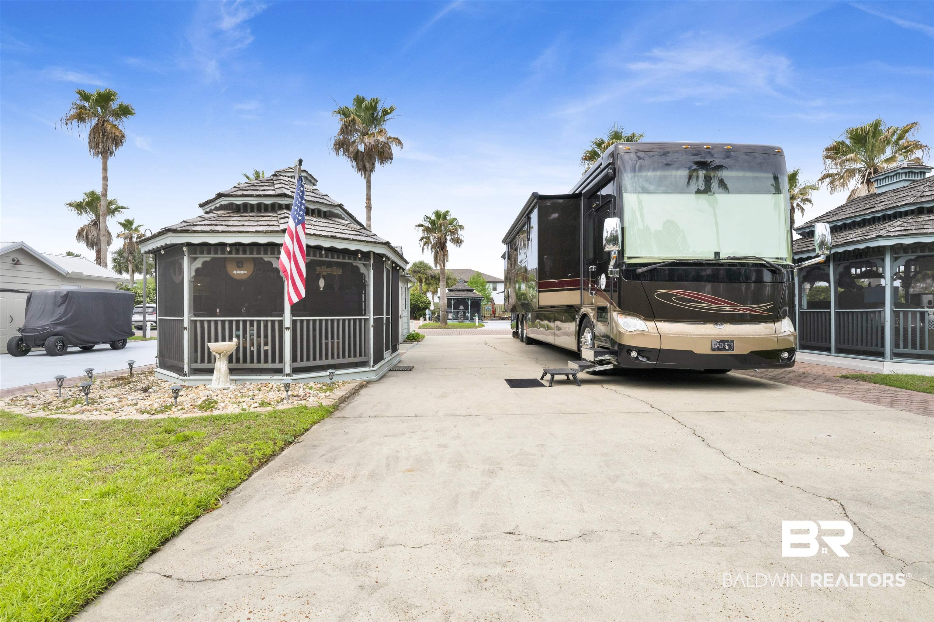 Image 3: Spacious concrete pad with an adjacent screened gazebo featuring a multi-tiered roof and louvered balustrade
