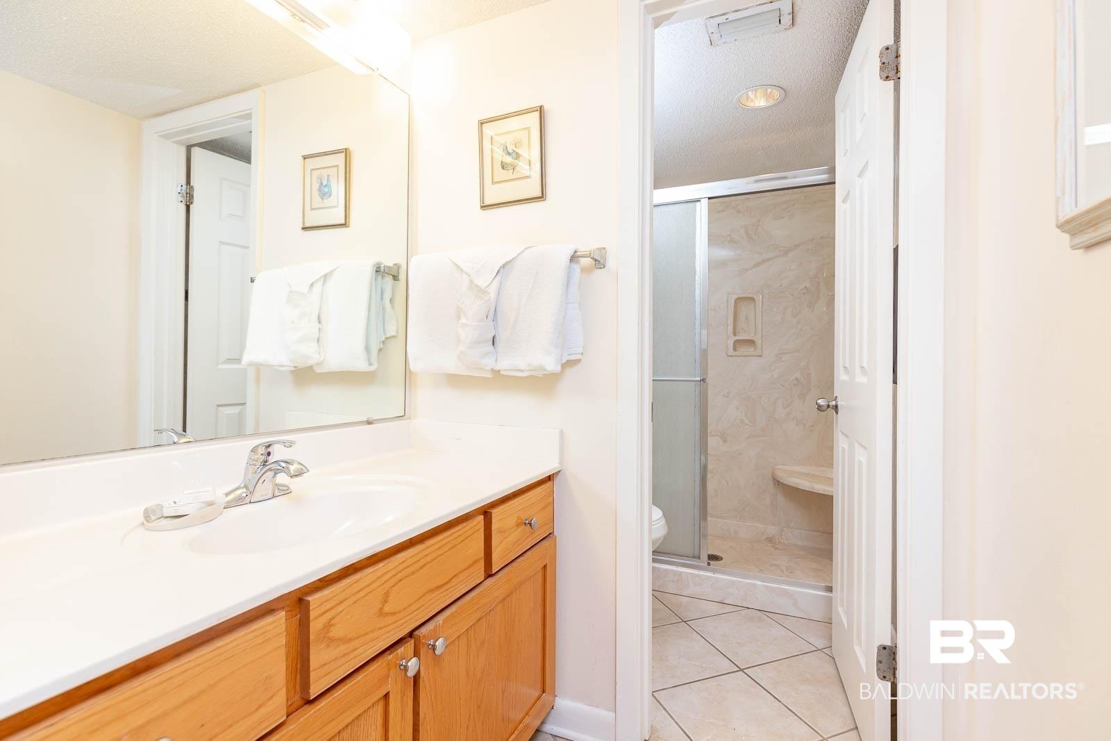 Image 4: Full bathroom featuring vanity, a stall shower, light tile patterned floors, and a textured ceiling
