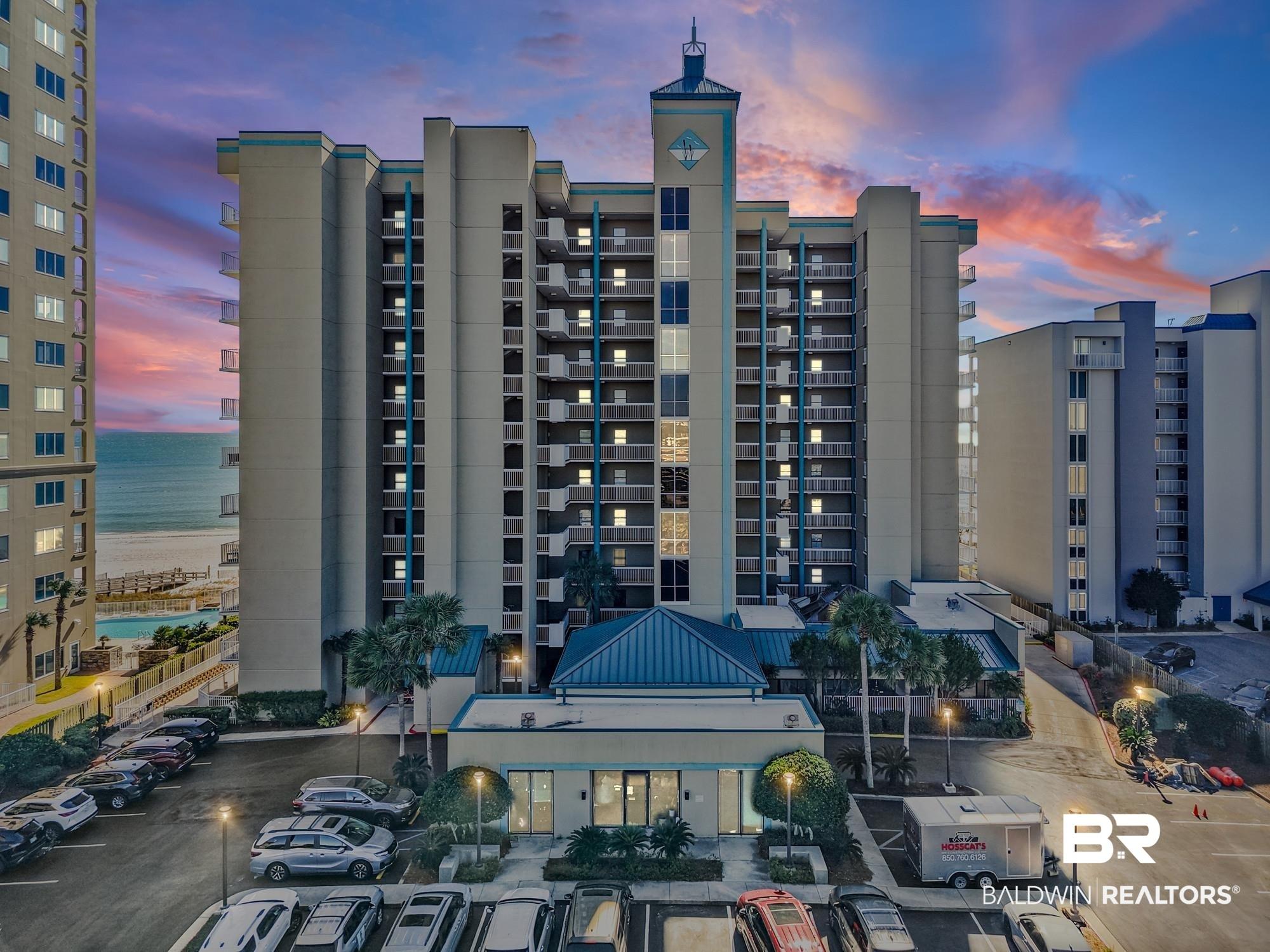 Image 2: Multi-story residential tower featuring numerous private balconies, a distinctive cupola-style architectural element, and a ground-level amenity building with a pitched roof