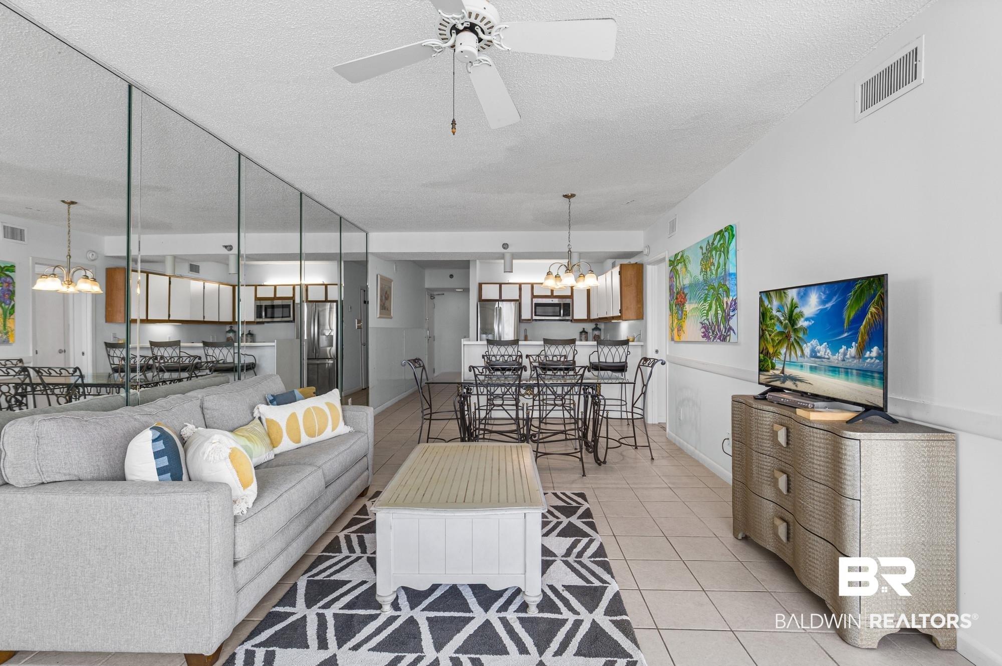 Image 4: Open-concept living area with neutral tile flooring