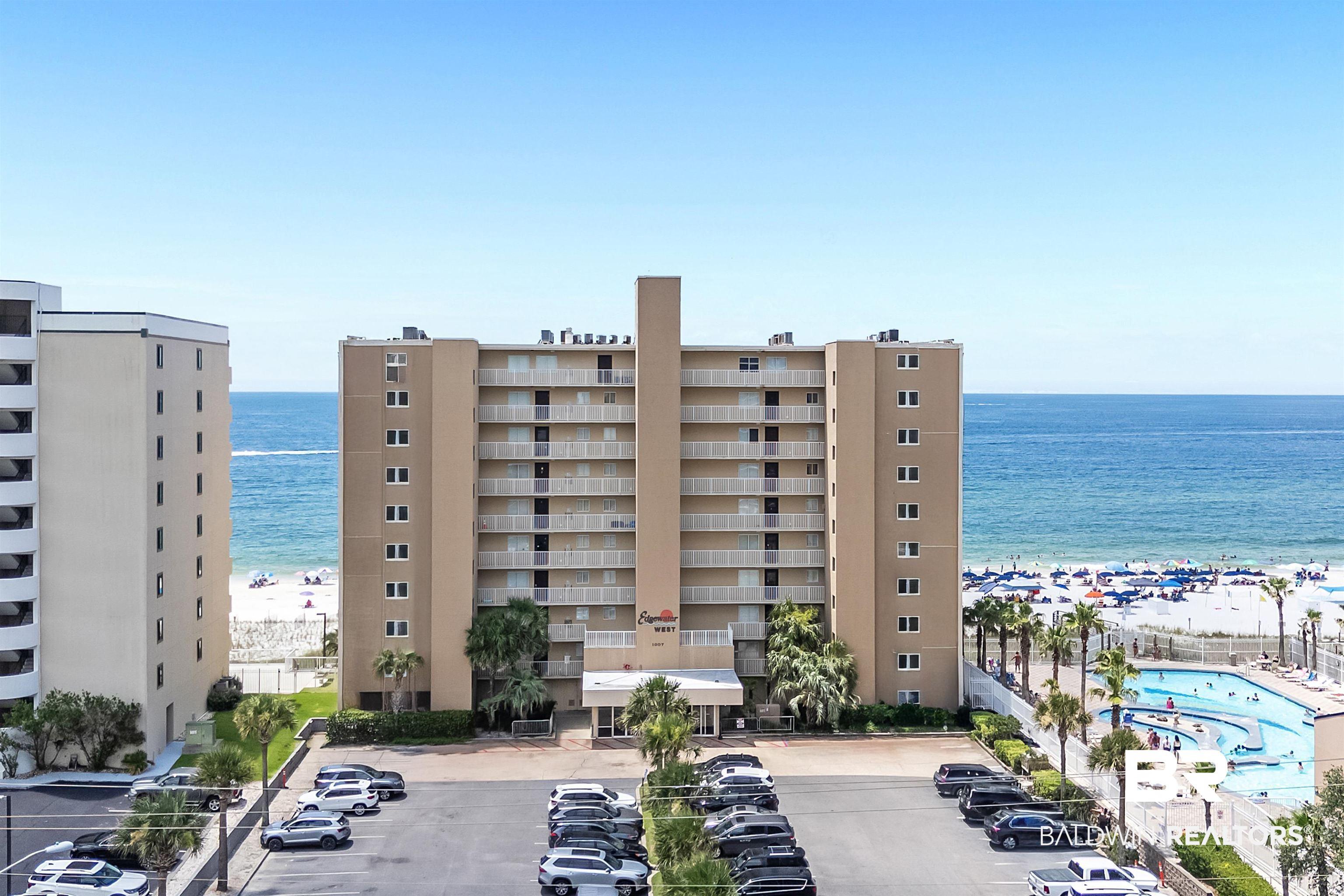 Image 1: View of building exterior featuring uncovered parking and view of water and beach