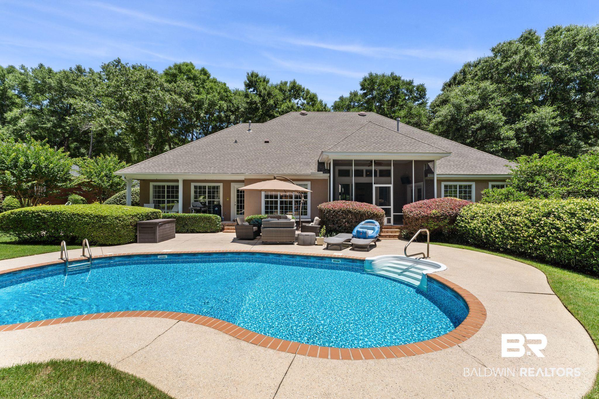 Image 3: Resort-style backyard featuring a kidney-shaped swimming pool with concrete decking, a screened-in porch, and a private patio area