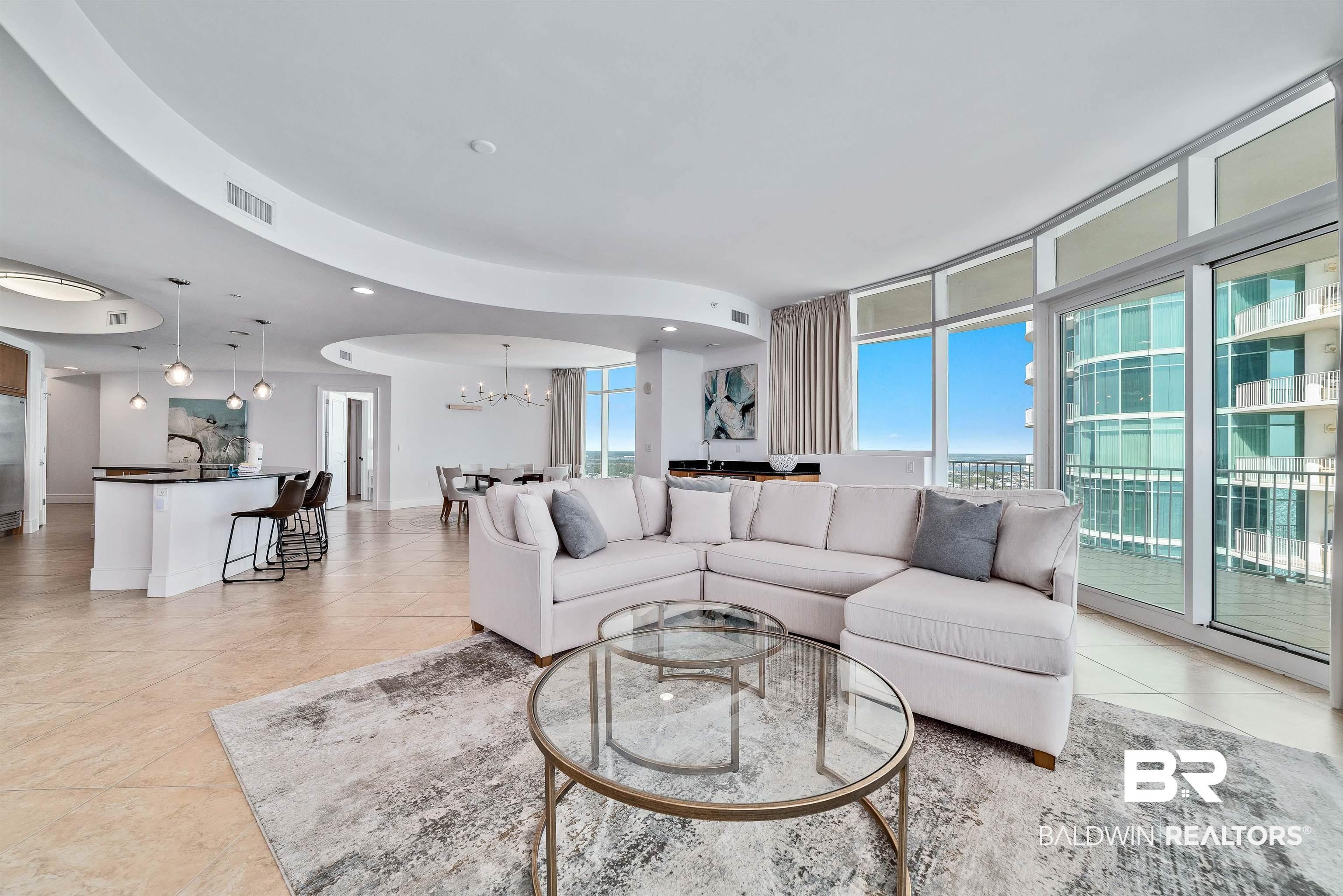Image 2: Living area with light tile patterned floors, a notable chandelier, visible vents, and a wealth of natural light