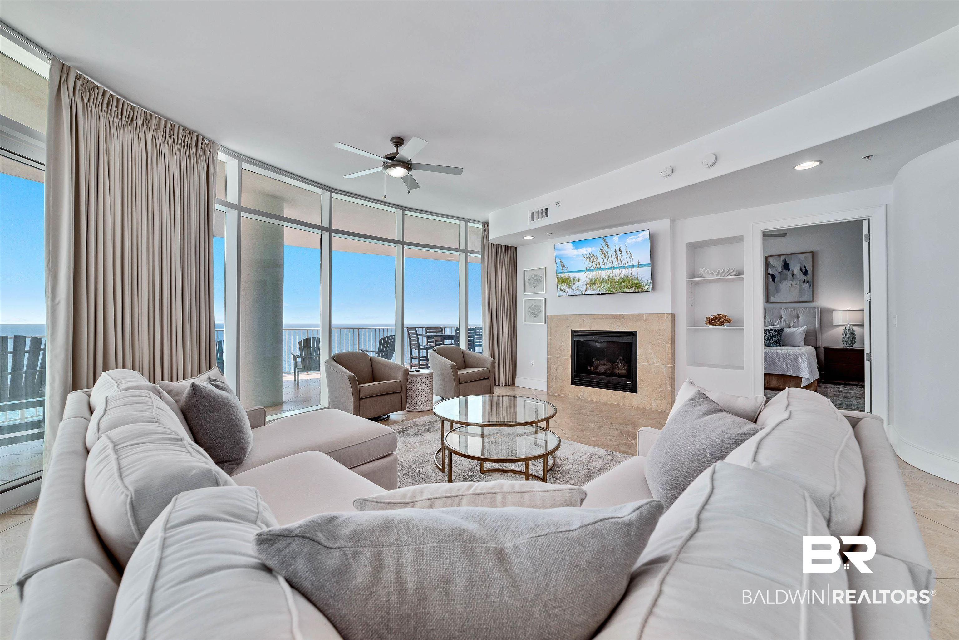 Image 4: Living area featuring visible vents, built in shelves, a tiled fireplace, floor to ceiling windows, and ceiling fan