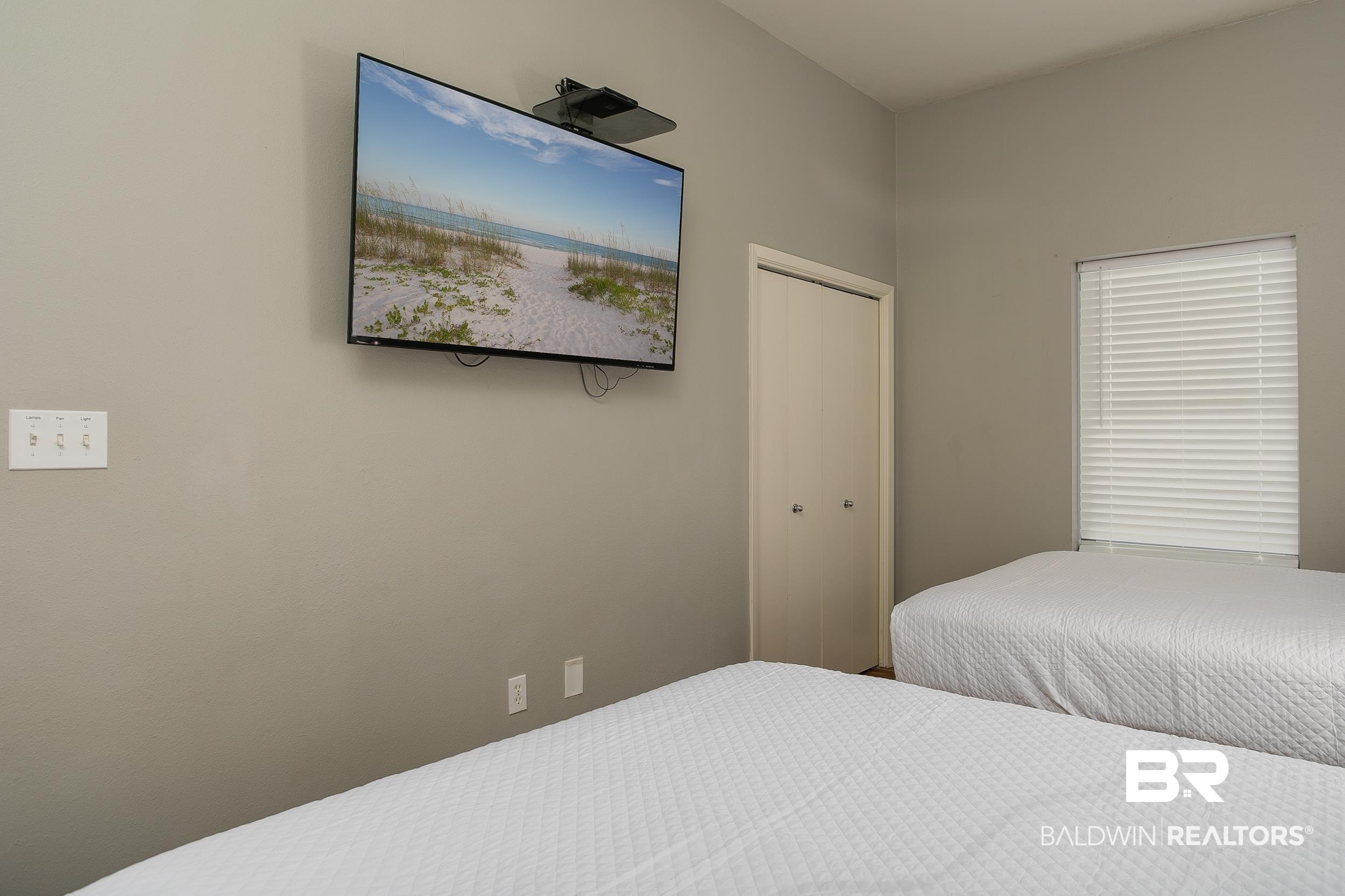 Image 3: Wall-mounted television and window with horizontal blinds