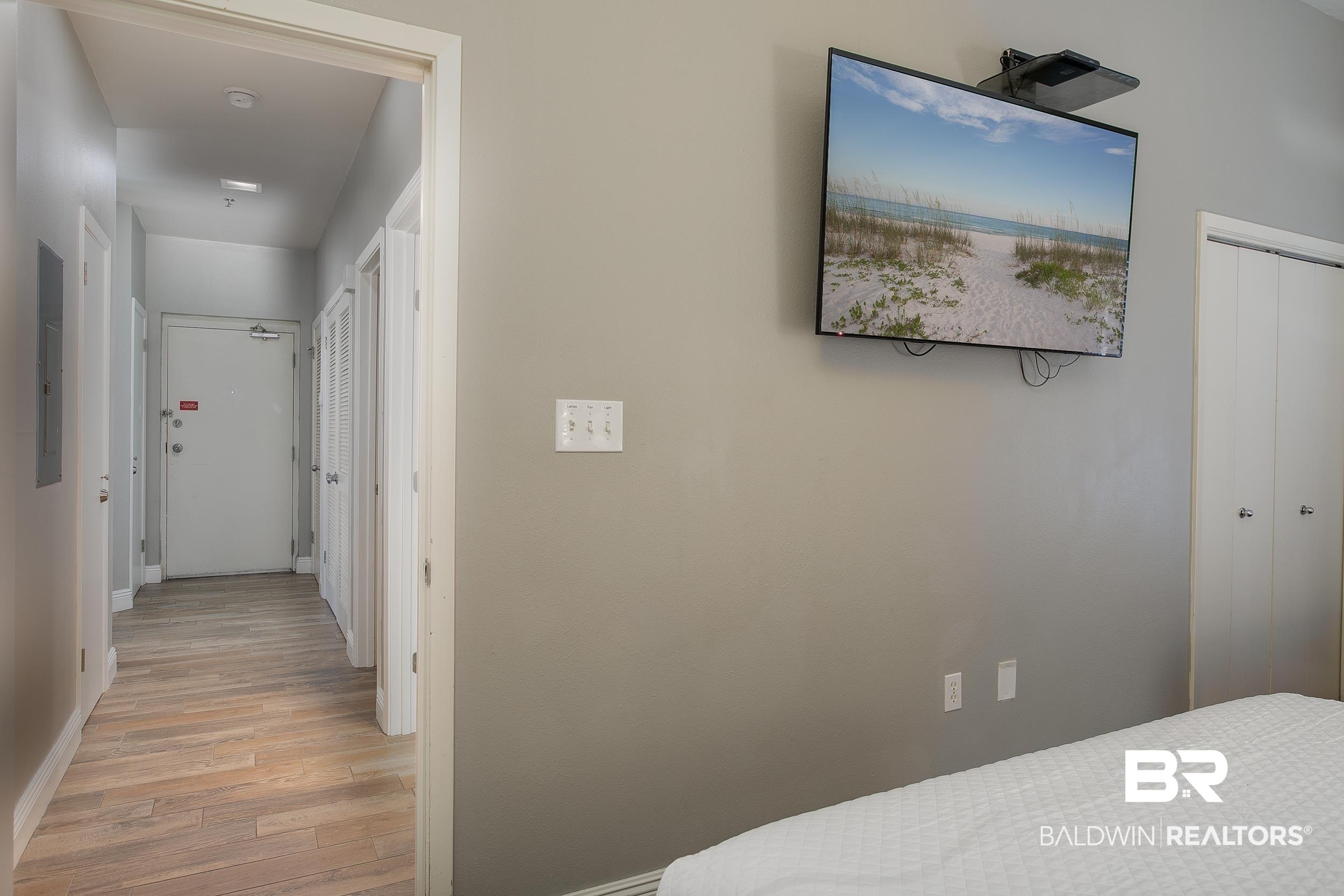 Image 4: Hallway featuring wood-finish flooring, light gray walls, and multiple white doors