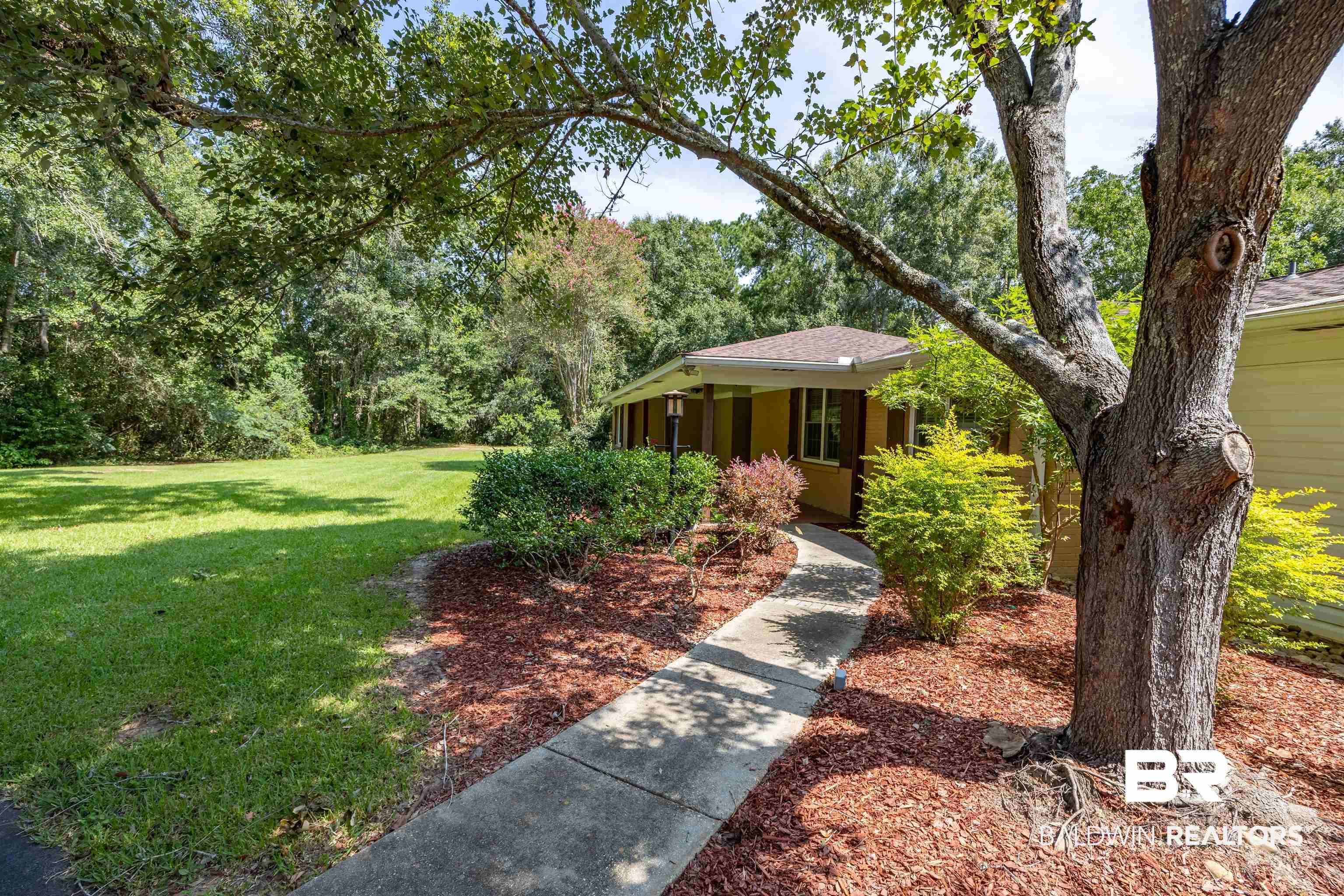 Image 1: Exterior showcasing a tan facade with dark shutters, a front porch, and a concrete walkway