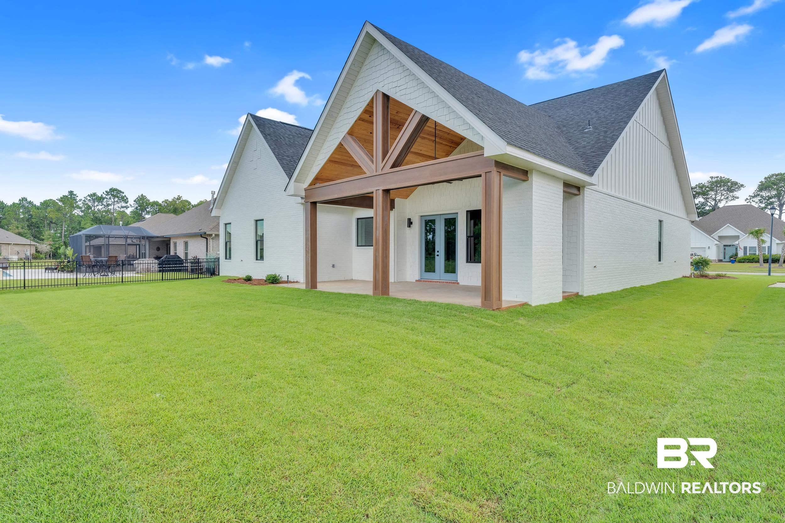 Image 2: Back of property with brick siding, a patio, roof with shingles, and french doors