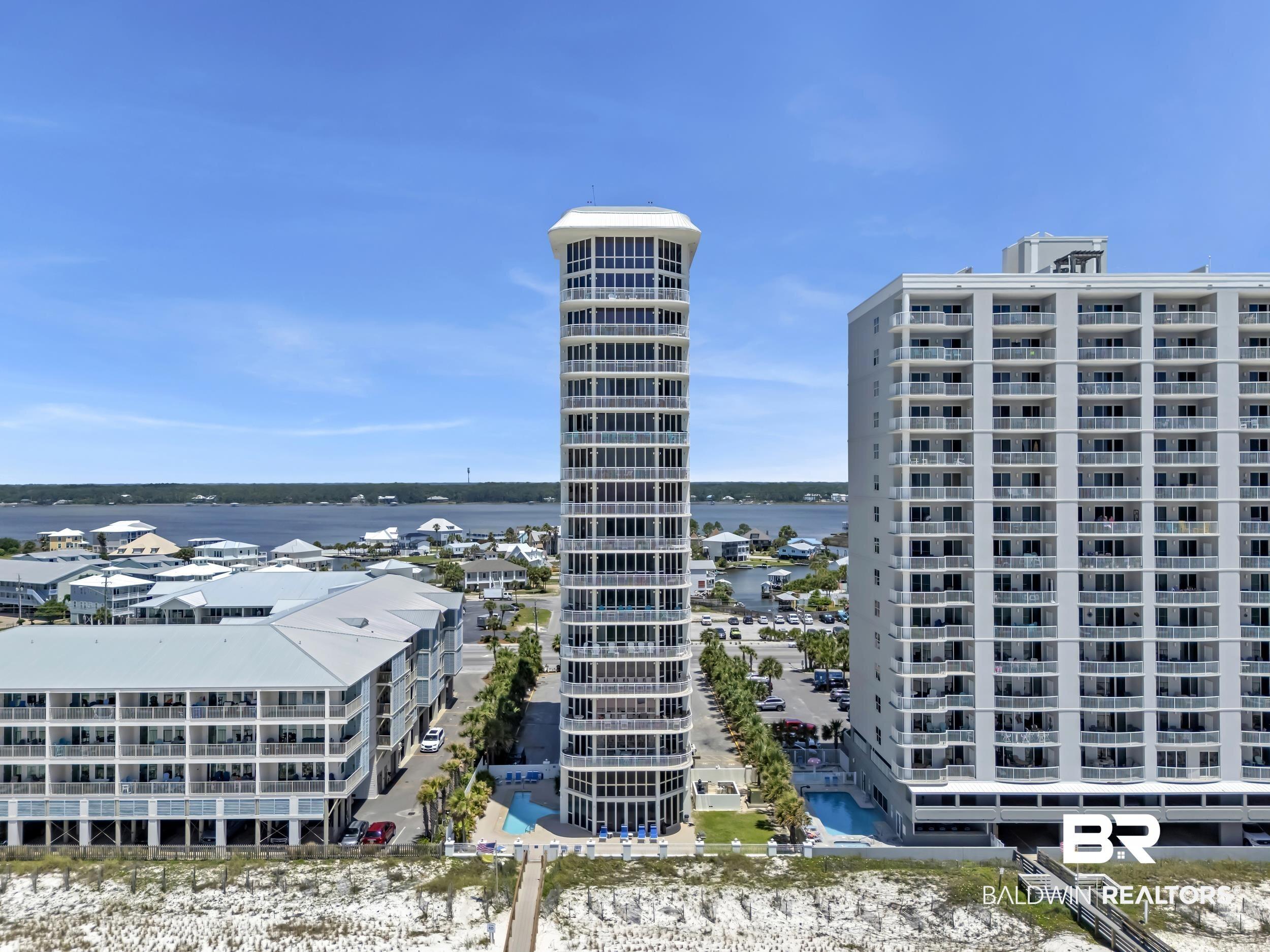Image 2: Modern high-rise tower with multiple balconies, a ground-level pool, and direct beach access via a wooden boardwalk