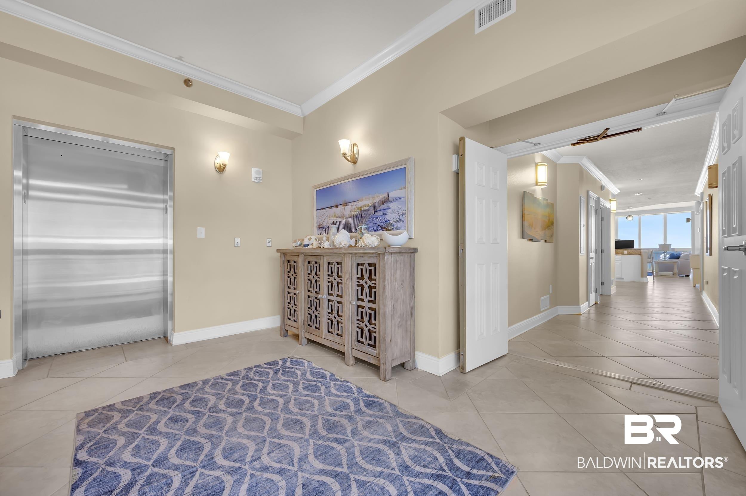 Image 3: Private elevator access to an entryway with tile flooring, crown molding, and recessed lighting