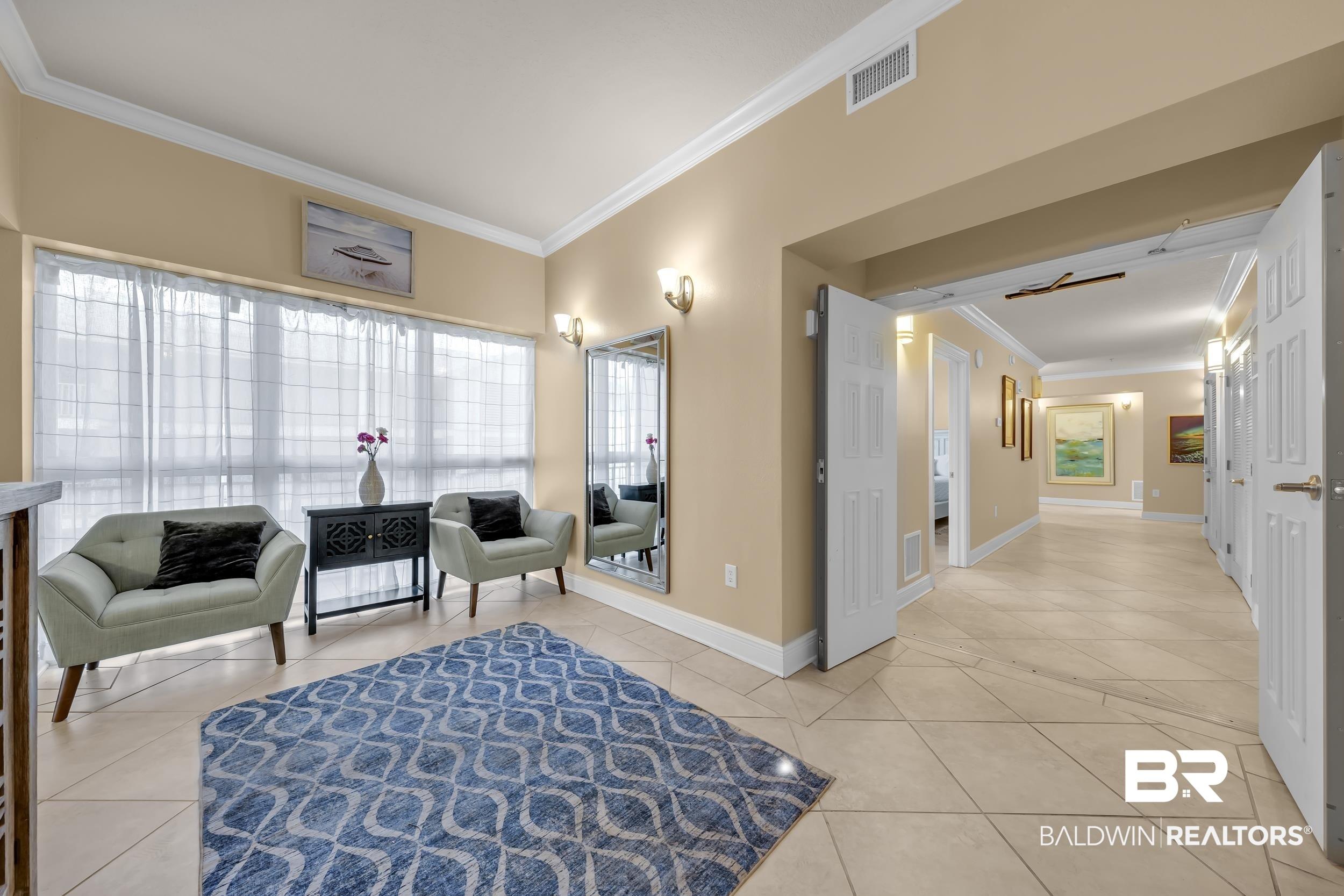 Image 4: Spacious entry area featuring light-toned tile flooring, tall baseboards, and crown molding