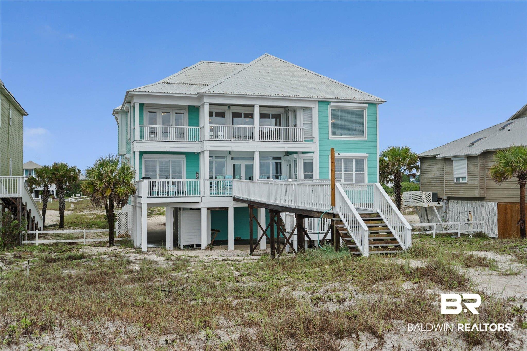Image 3: Multi-story coastal residence featuring a vibrant teal exterior, white trim, and a metal roof