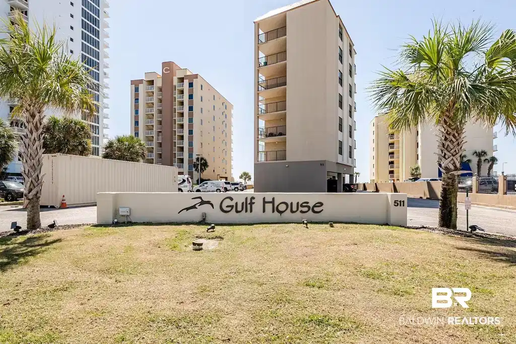 Image 1: Entryway signage for "Gulf House" featuring established palm trees, a manicured lawn area, and multi-story condominium buildings