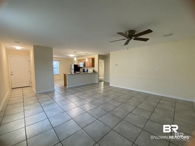 Image 2: Unfurnished living room with light tile patterned floors, a ceiling fan, and baseboards