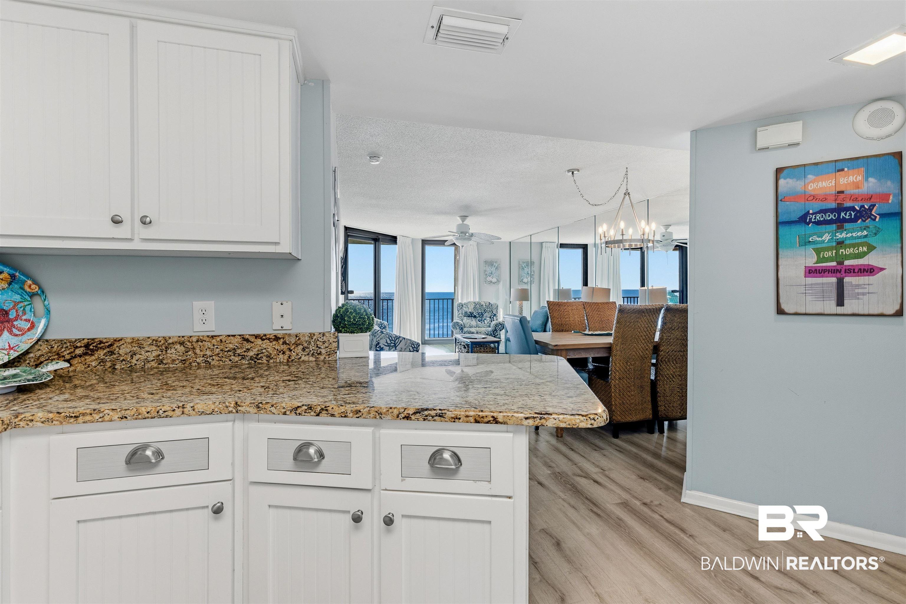 Image 4: Kitchen featuring white cabinetry, a peninsula, light wood-style flooring, light stone countertops, and open floor plan