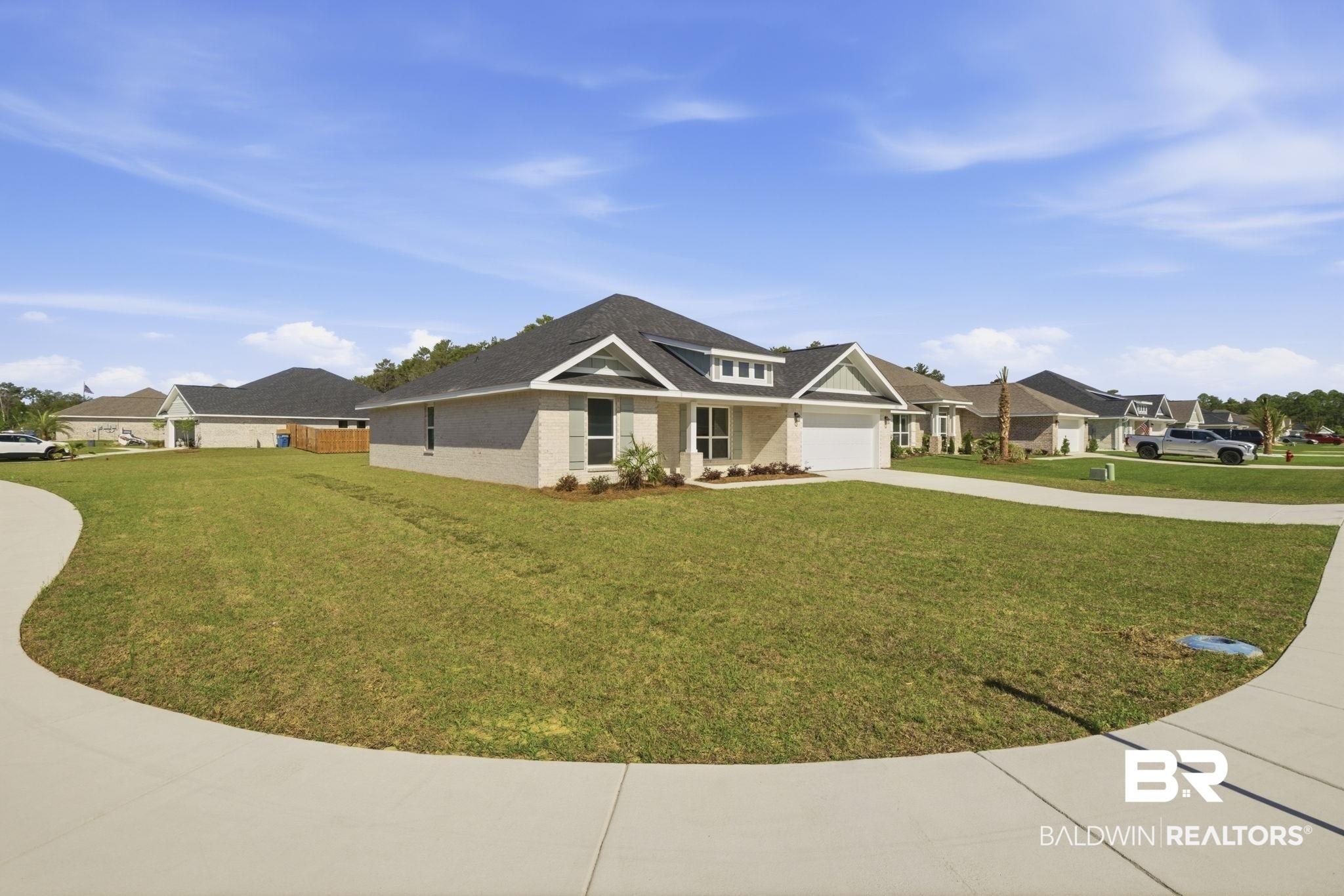 Image 3: View of front of property with a front lawn, driveway, an attached garage, and a residential view