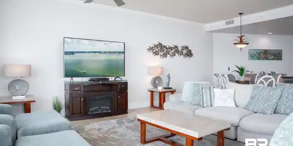 Image 4: Spacious living area featuring a ceiling fan with integrated lighting, crown molding, and a built-in media console with an electric fireplace