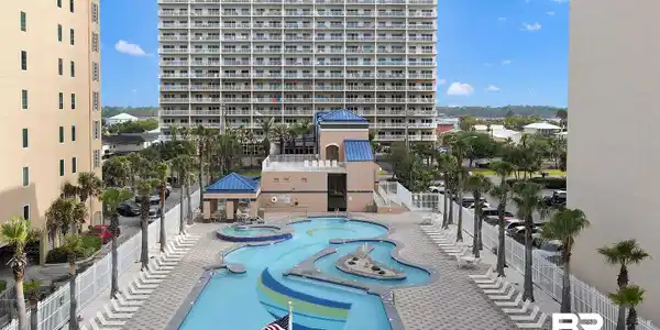 Image 2: Resort-style pool area featuring a large, irregularly shaped swimming pool with integrated water features, a separate hot tub, and an adjacent cabana structure