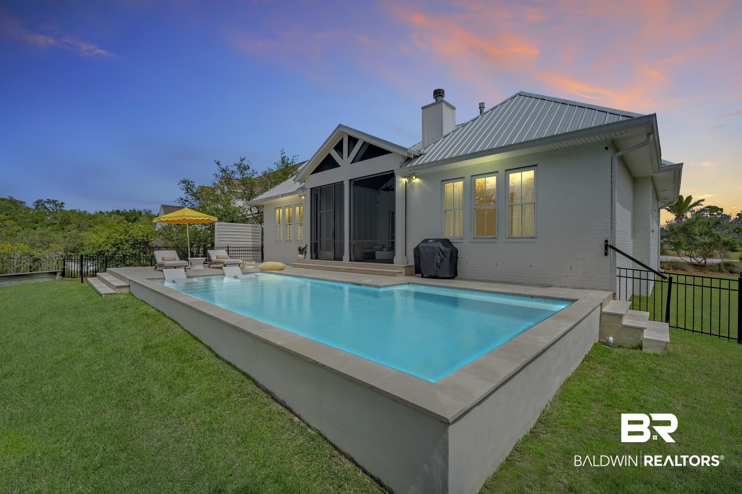 Image 2: Backyard oasis featuring a rectangular swimming pool with integrated water features, expansive lawn, and a screened porch