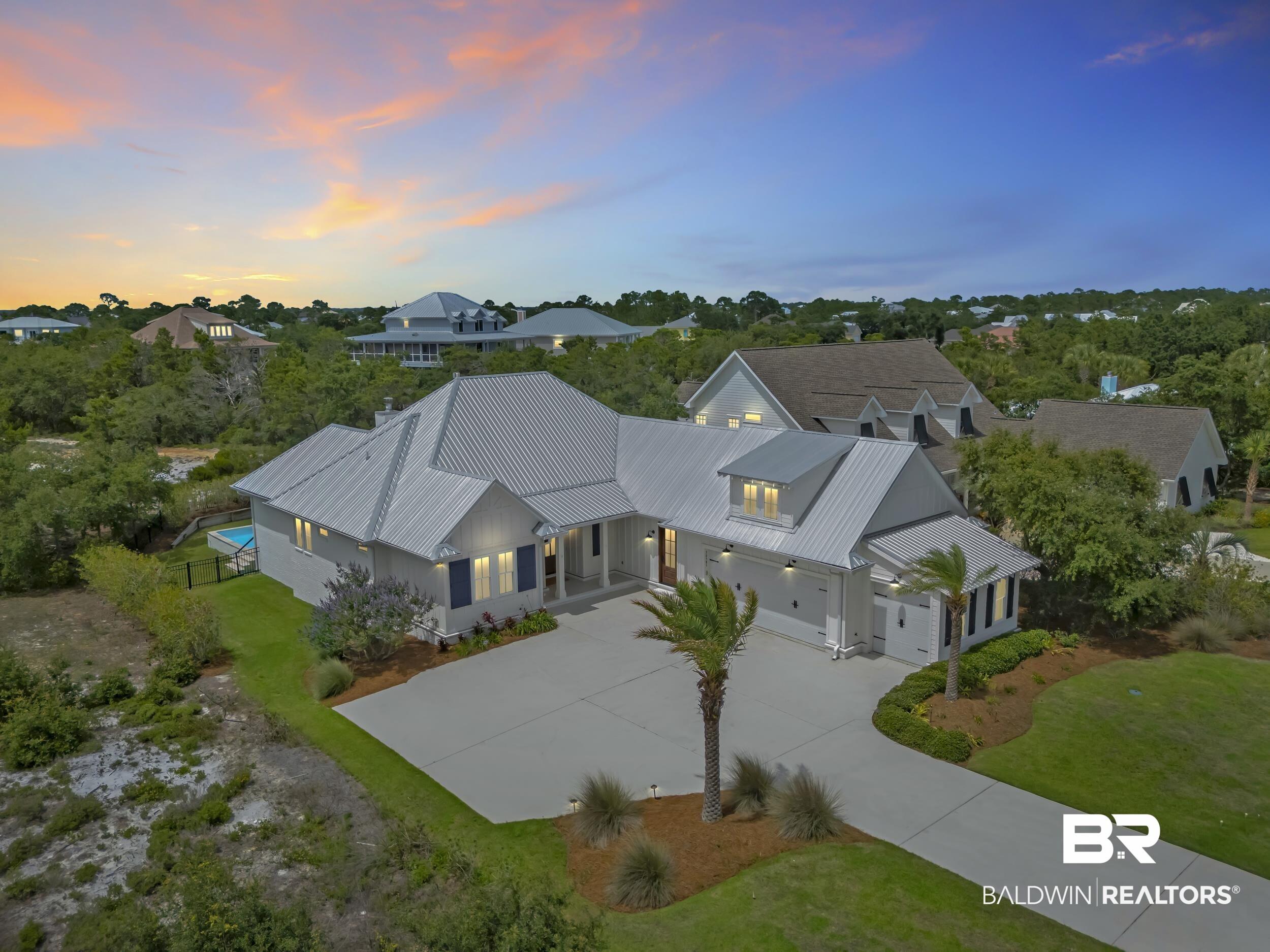 Image 4: Coastal-inspired residence featuring a light-colored exterior, metal roof, and attached garage