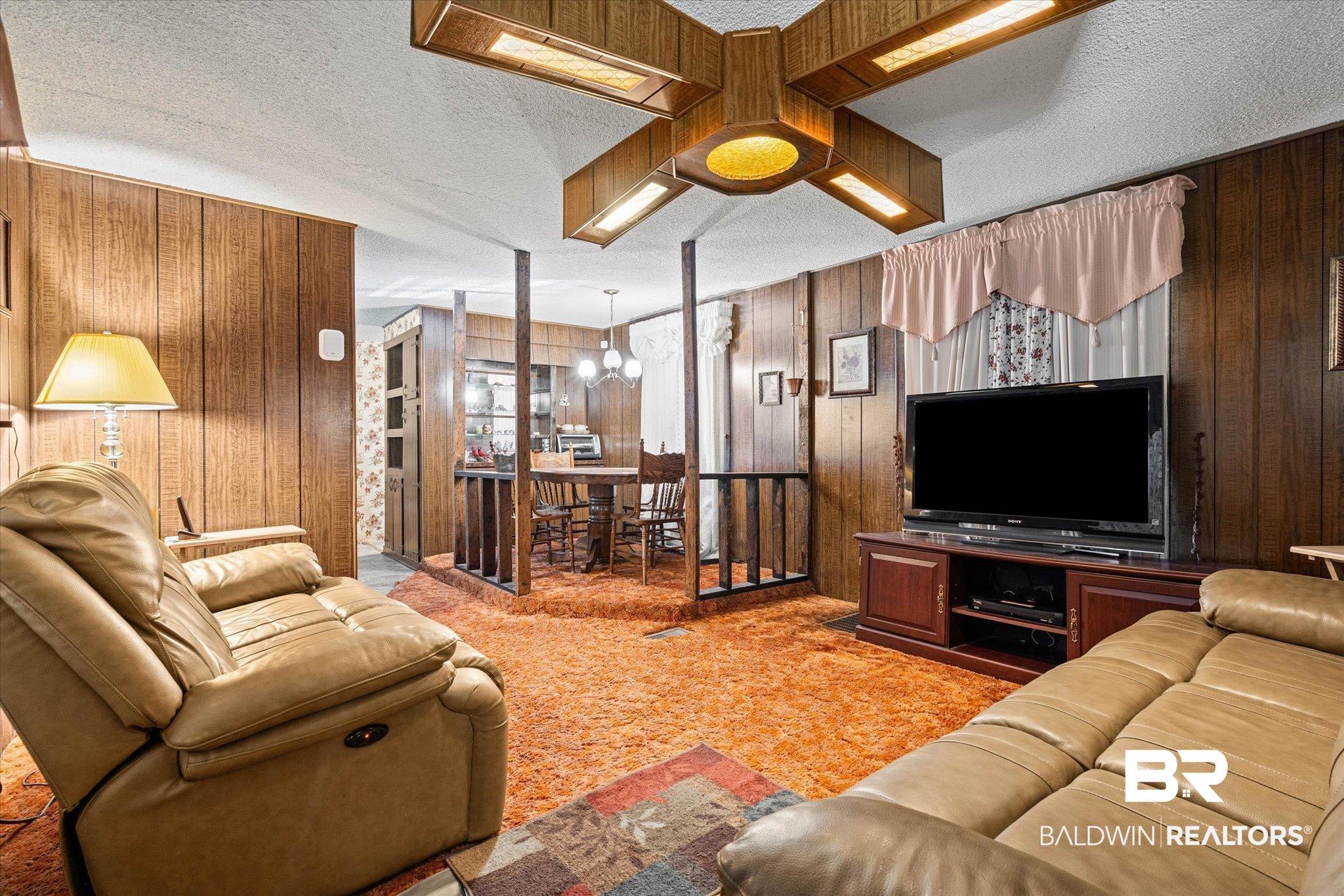 Image 3: Living area featuring wood paneling, textured ceiling, and an integrated ceiling light fixture