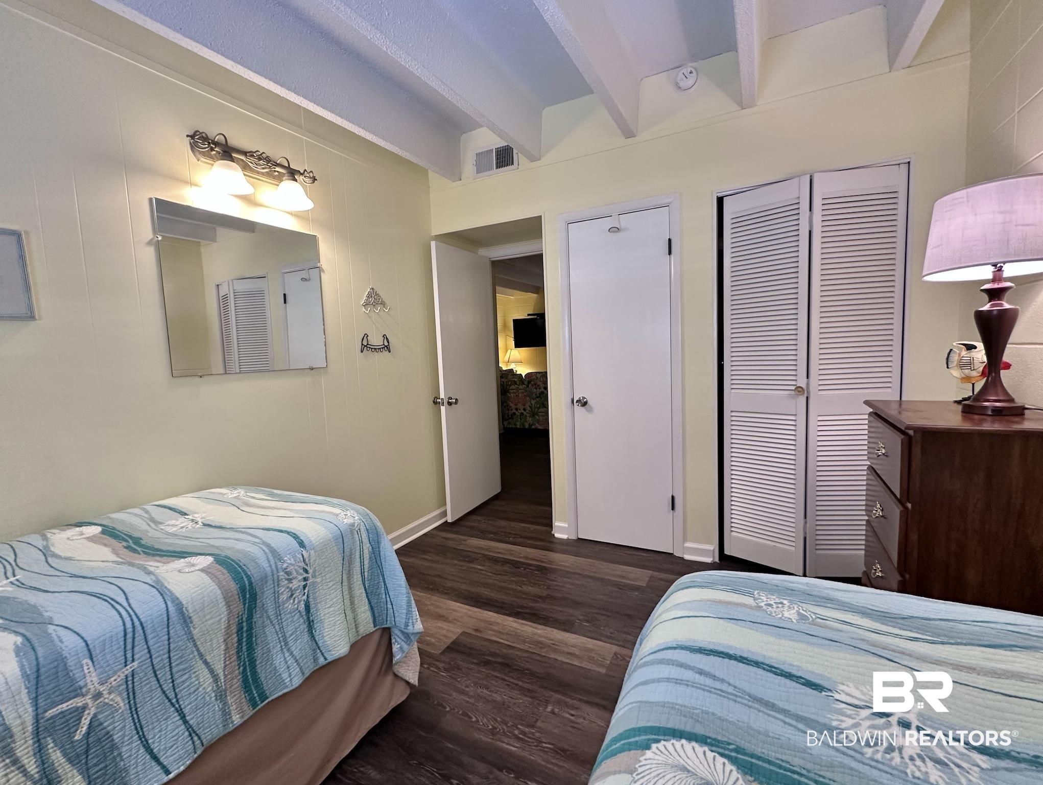 Image 4: Bedroom featuring beam ceiling, dark wood-style flooring, and a closet