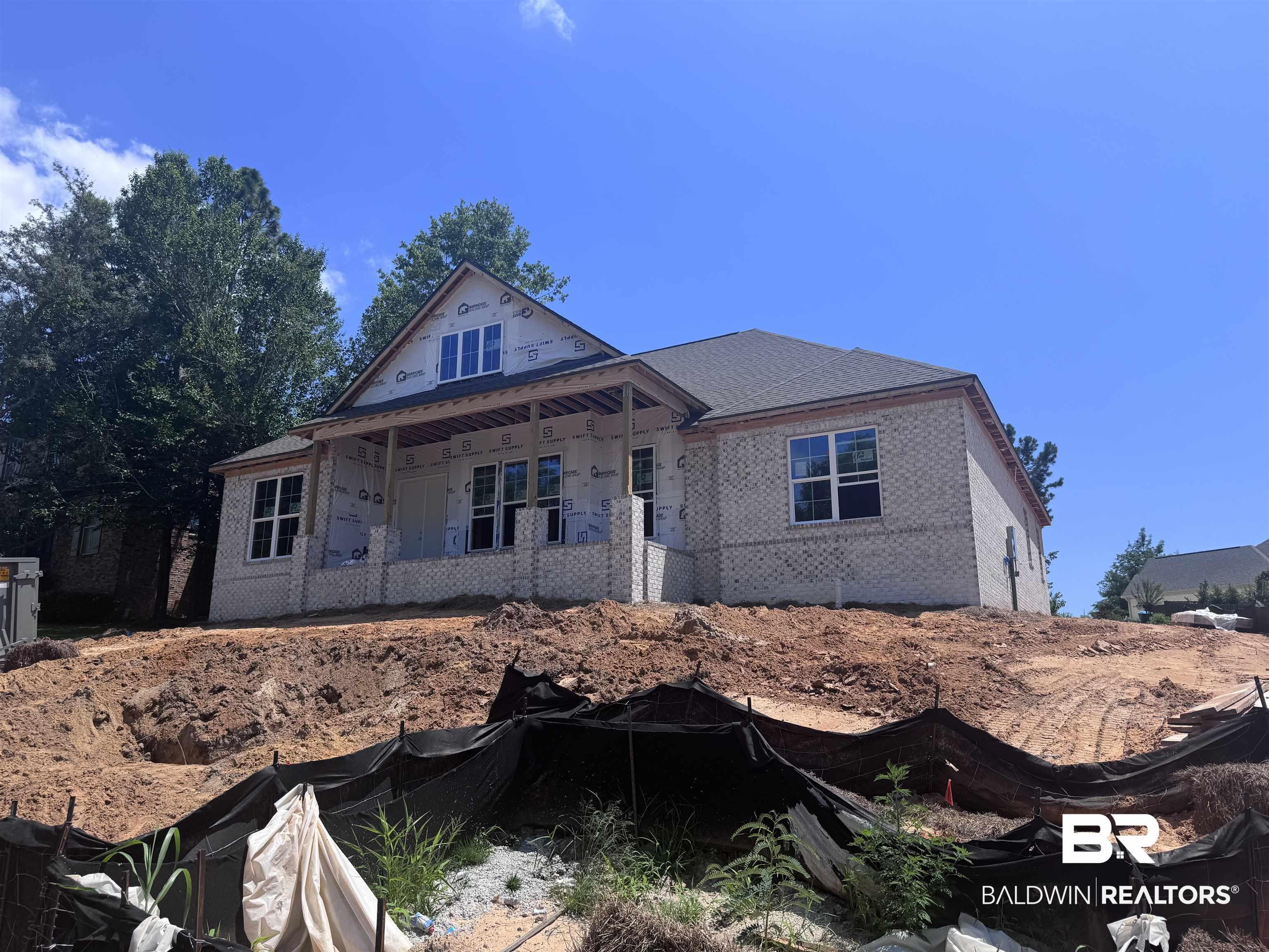 Image 2: New construction residence featuring a light-colored brick facade and a dark shingle roof
