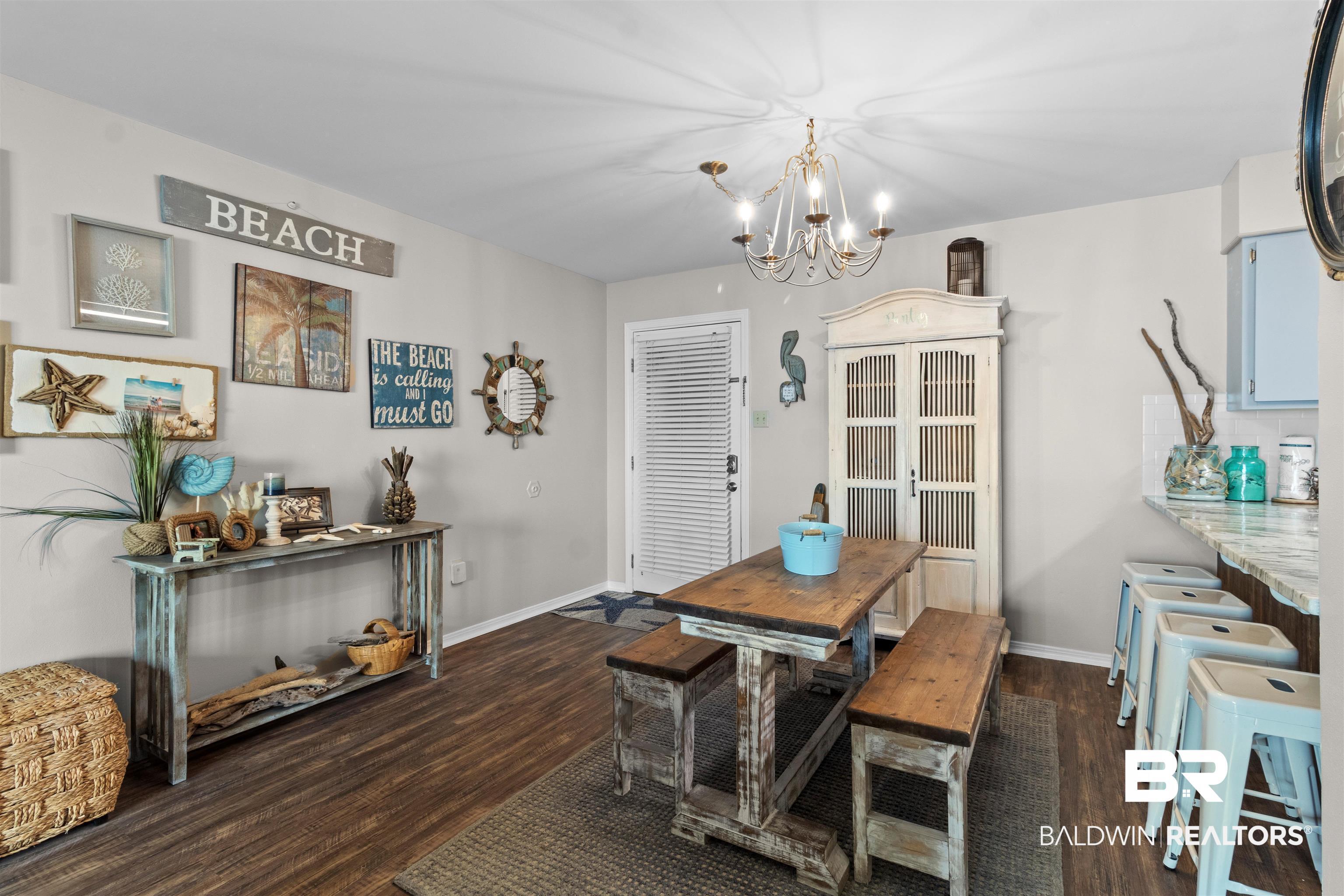 Image 3: Dining area featuring wood-finish flooring, a decorative chandelier, and a breakfast bar with seating