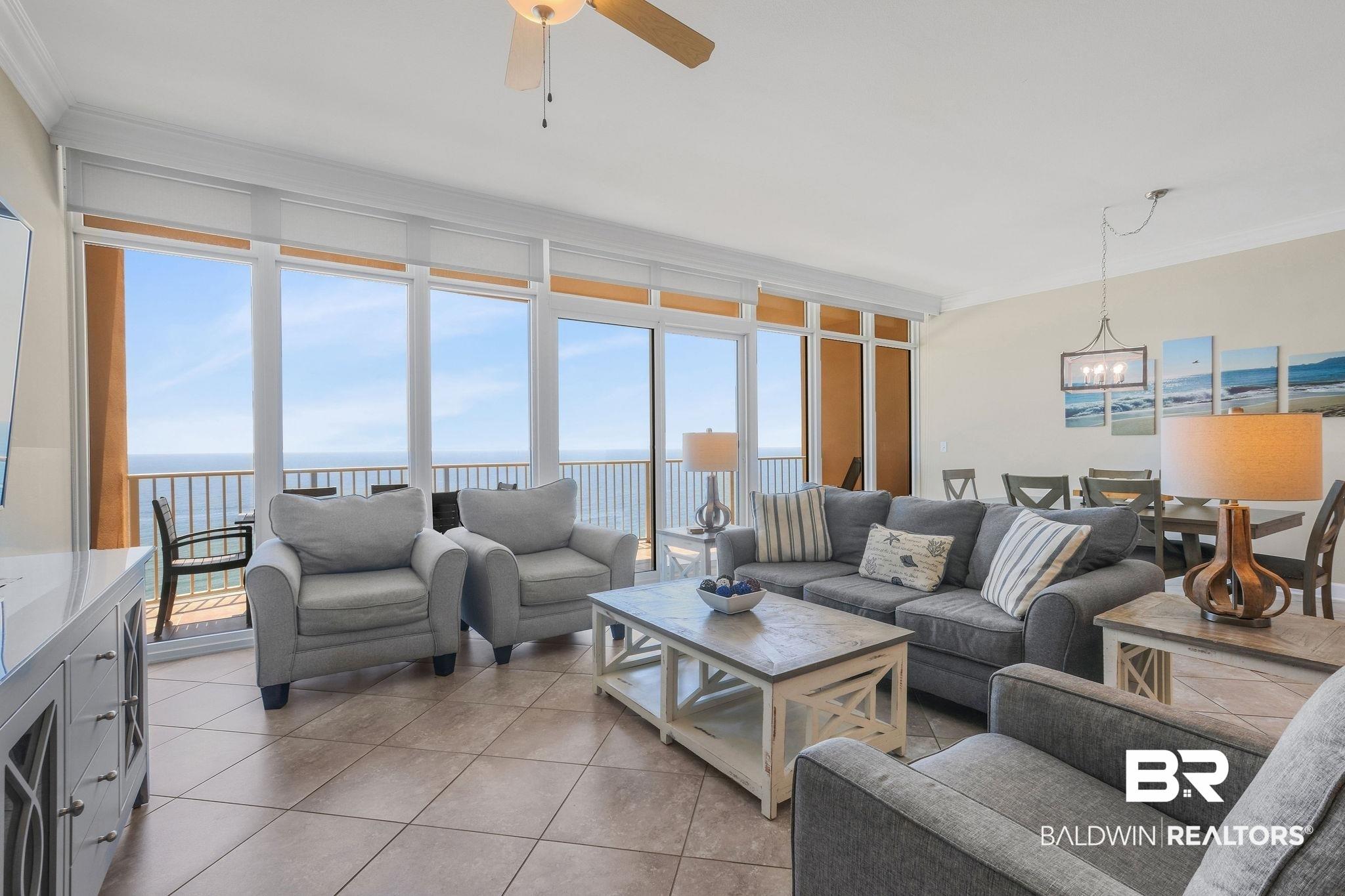 Image 2: Living area with a water view, a wall of windows, light tile patterned floors, crown molding, and a ceiling fan