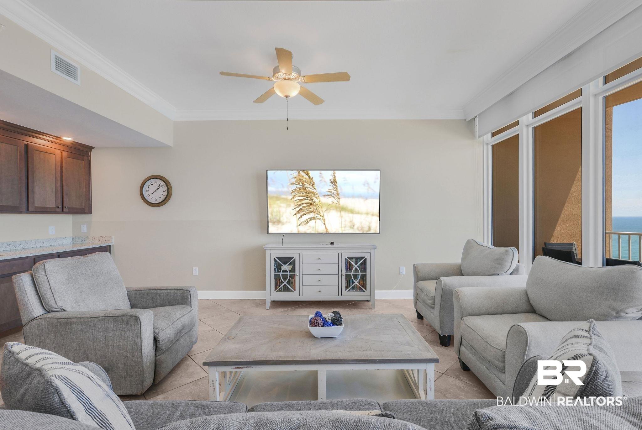 Image 4: Living room with ornamental molding, light tile patterned flooring, and ceiling fan