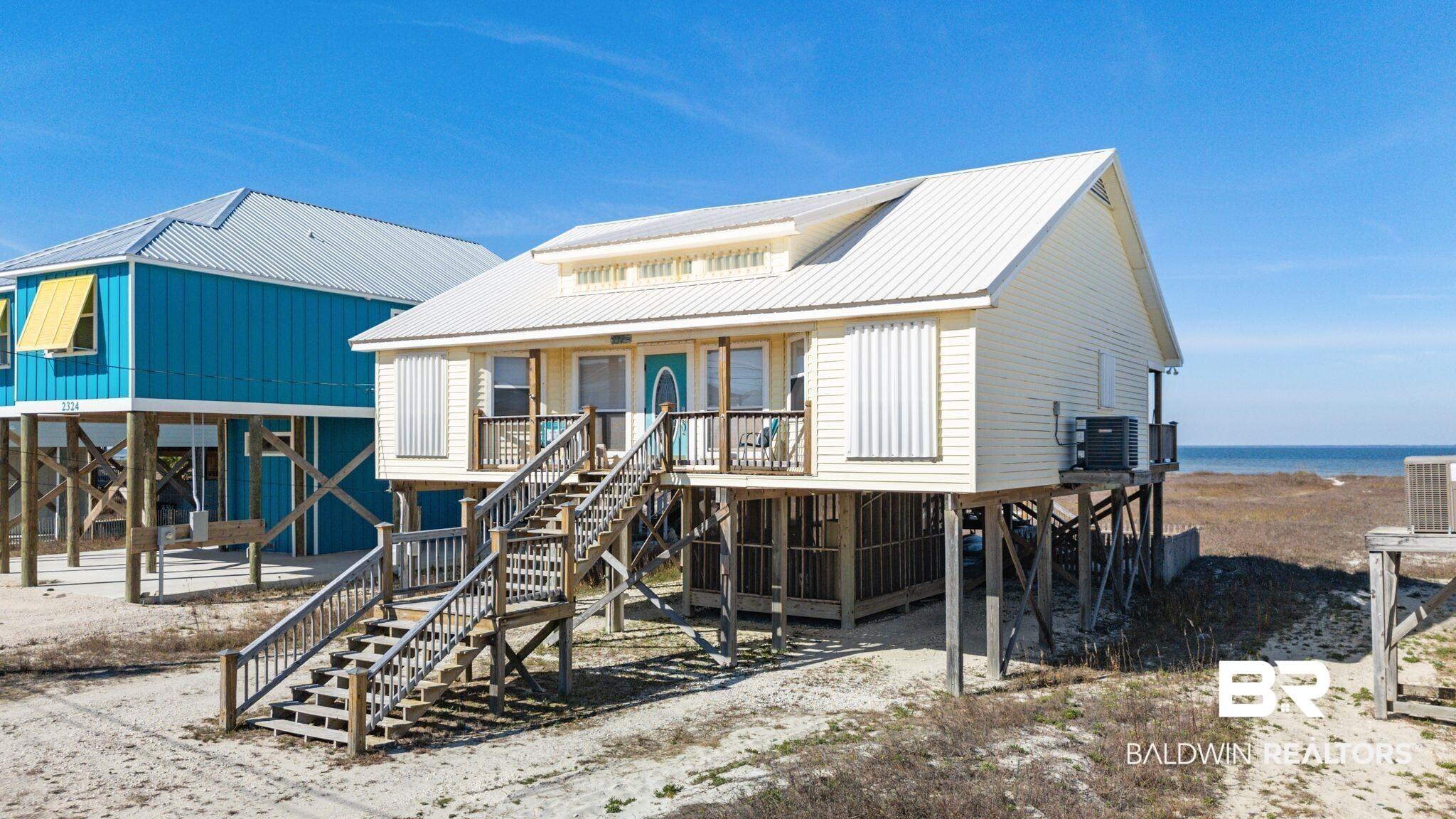 Image 2: Rear view of house featuring stairway, a metal roof, and a carport
