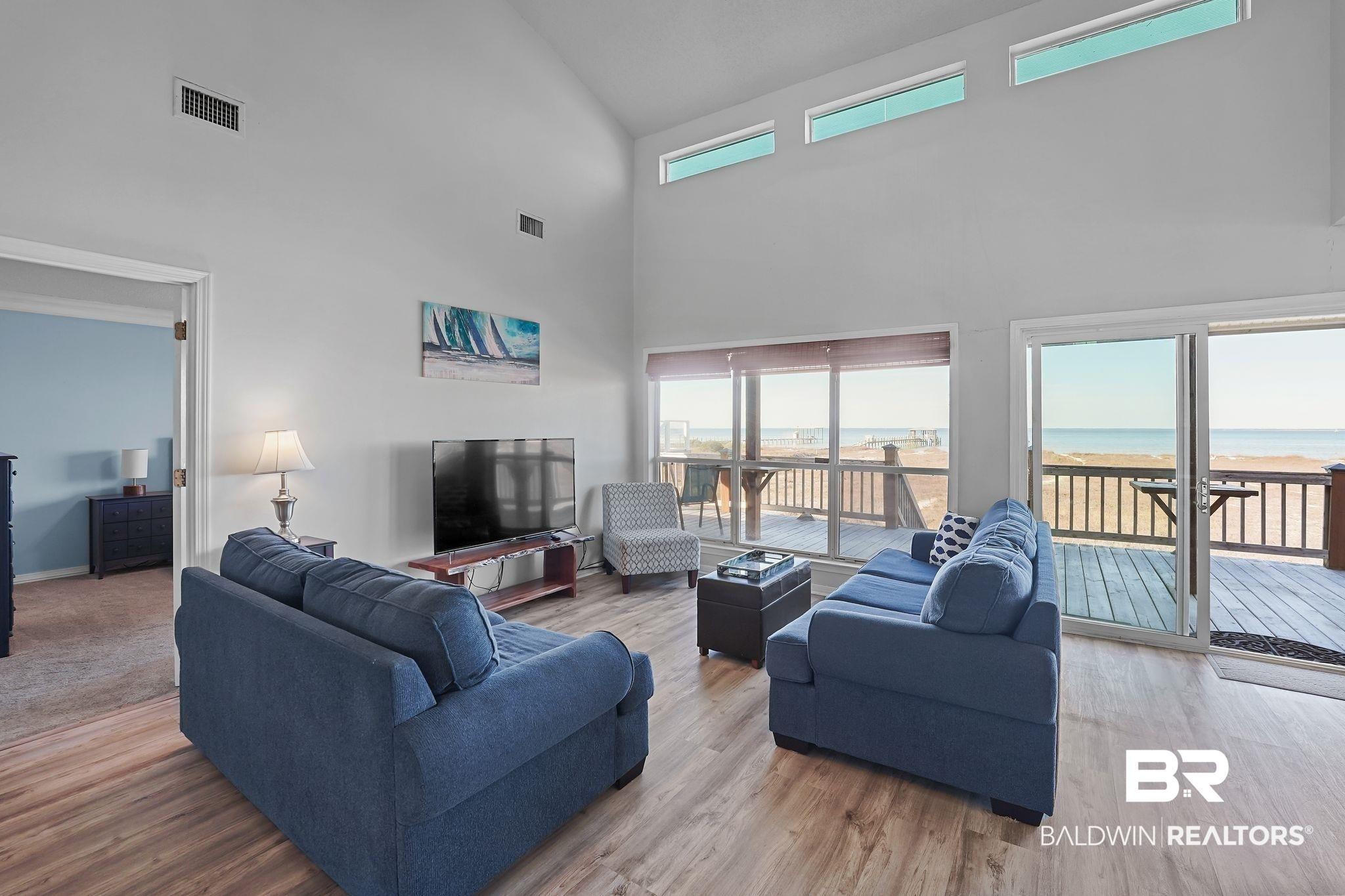Image 4: Living area with light wood-style floors and high vaulted ceiling