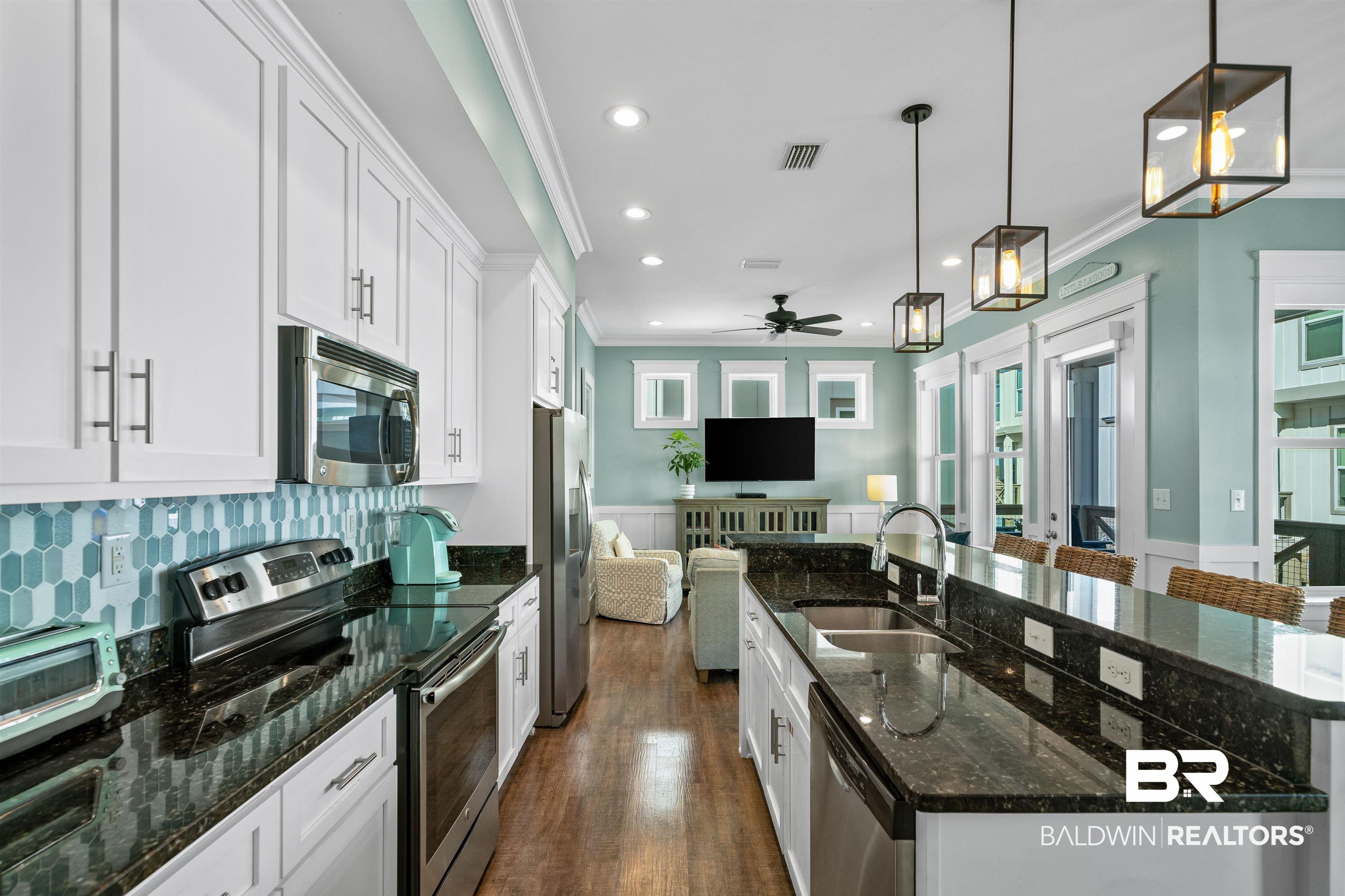 Image 4: Kitchen with stainless steel appliances, dark stone counters, white cabinets, a kitchen island with sink, and crown molding