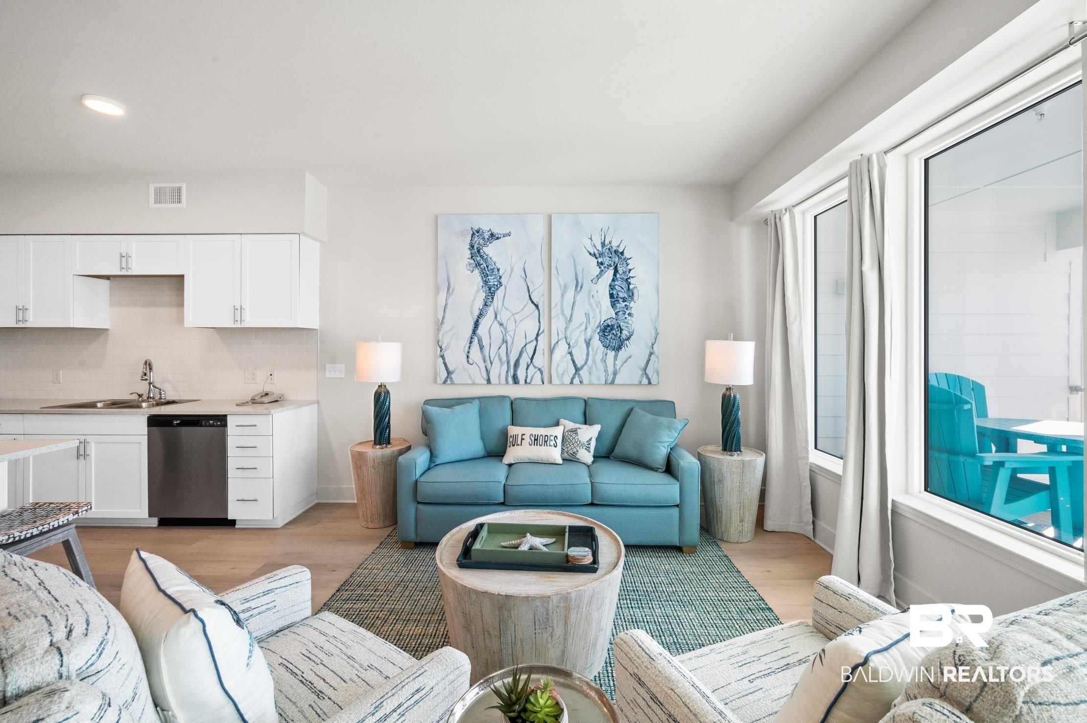 Image 3: Open-concept living area featuring light wood-finish flooring and a kitchen with white cabinetry