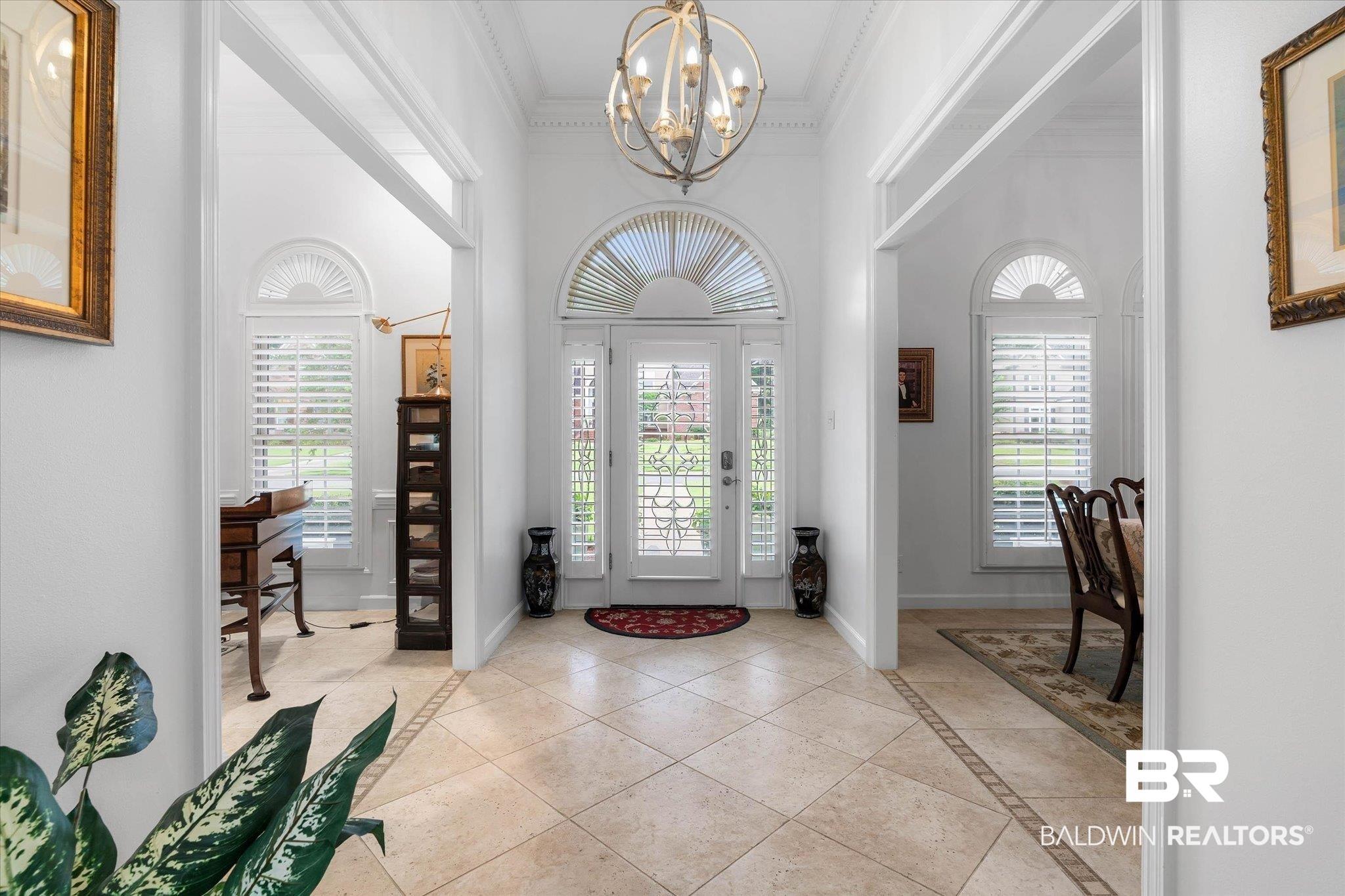 Image 2: Entry foyer featuring tile flooring with a decorative inlay, a double-door entry with leaded glass, and an arched transom window