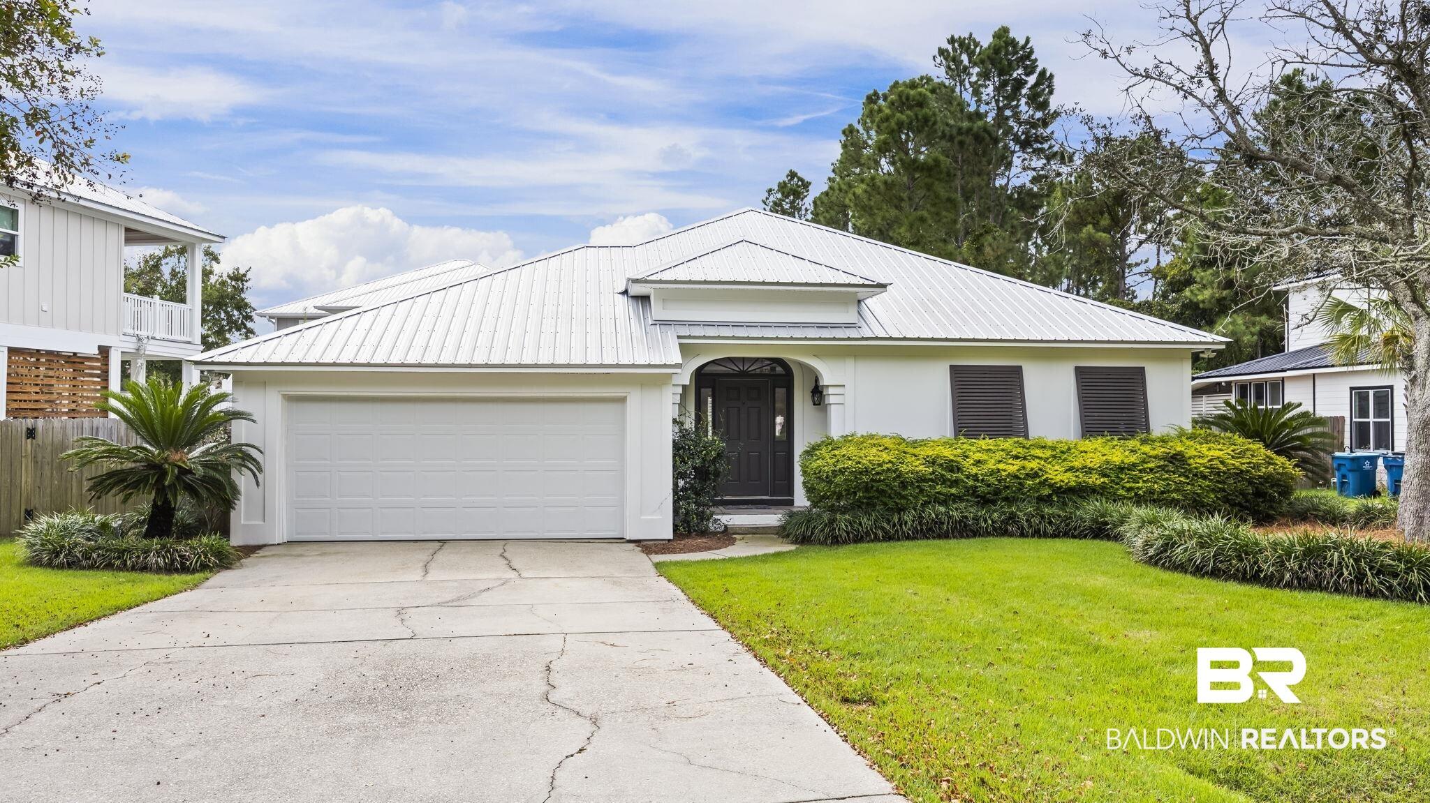 Image 2: View of front of home featuring a metal roof, concrete driveway, a garage, and stucco siding