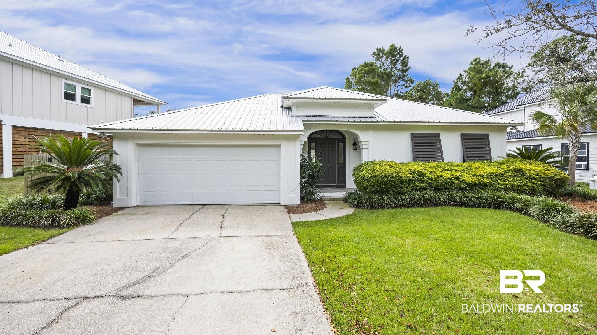 Image 4: View of front of house with concrete driveway, a front yard, a metal roof, and a garage