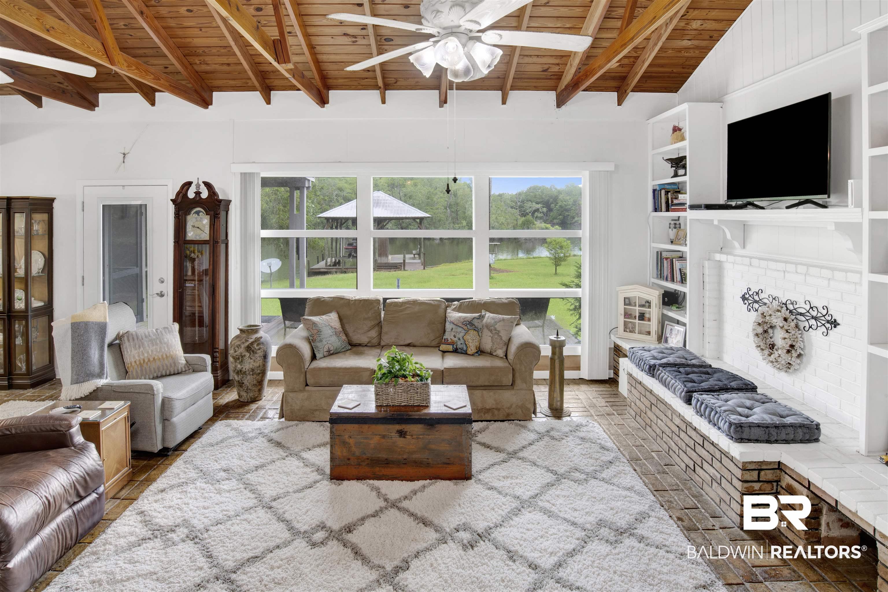 Image 3: Living room featuring wood ceiling, ceiling fan, a brick fireplace, lofted ceiling with beams, and built in features