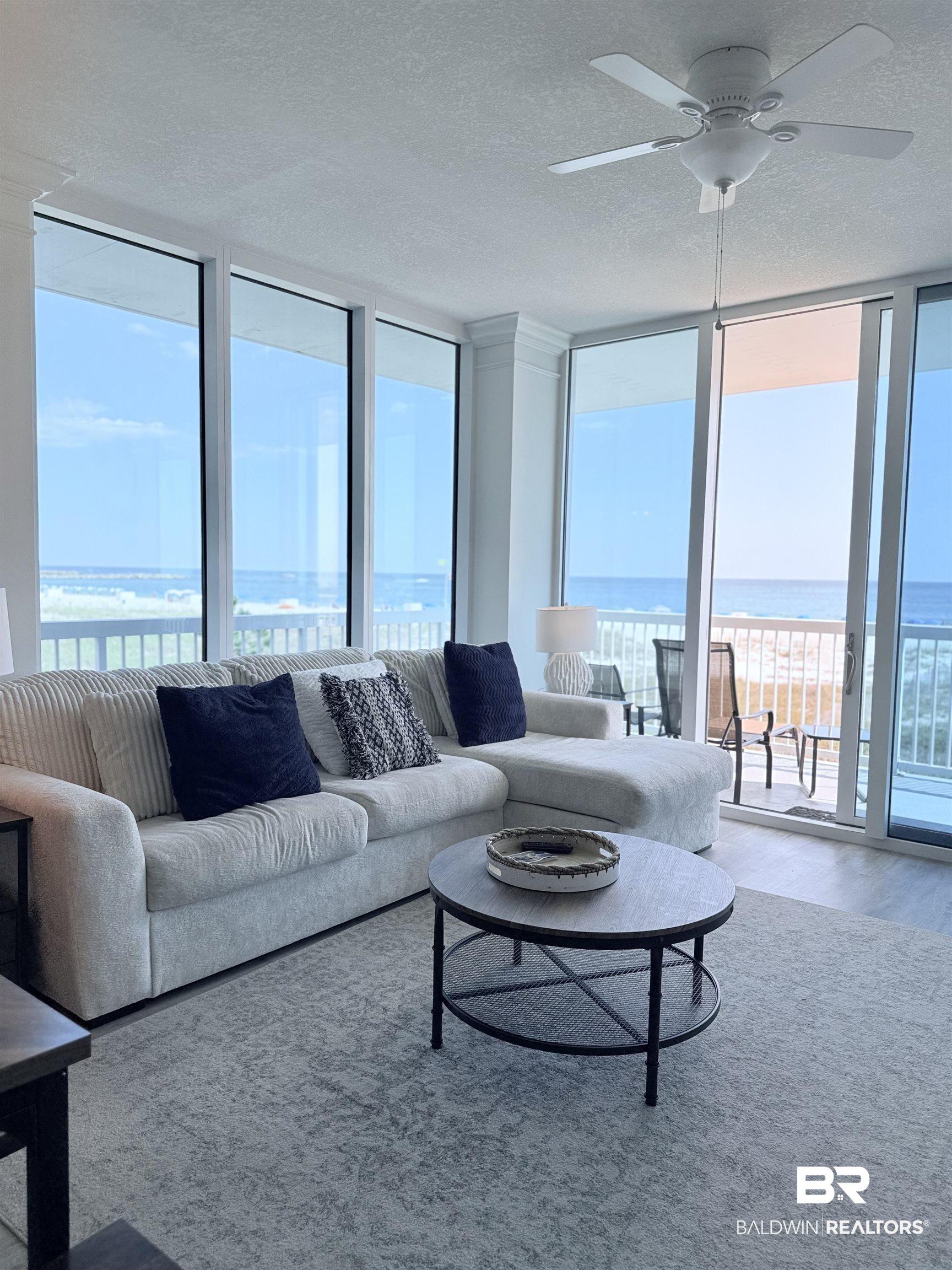 Image 3: Living room with expansive windows, a textured ceiling, wood finished floors, and a water view
