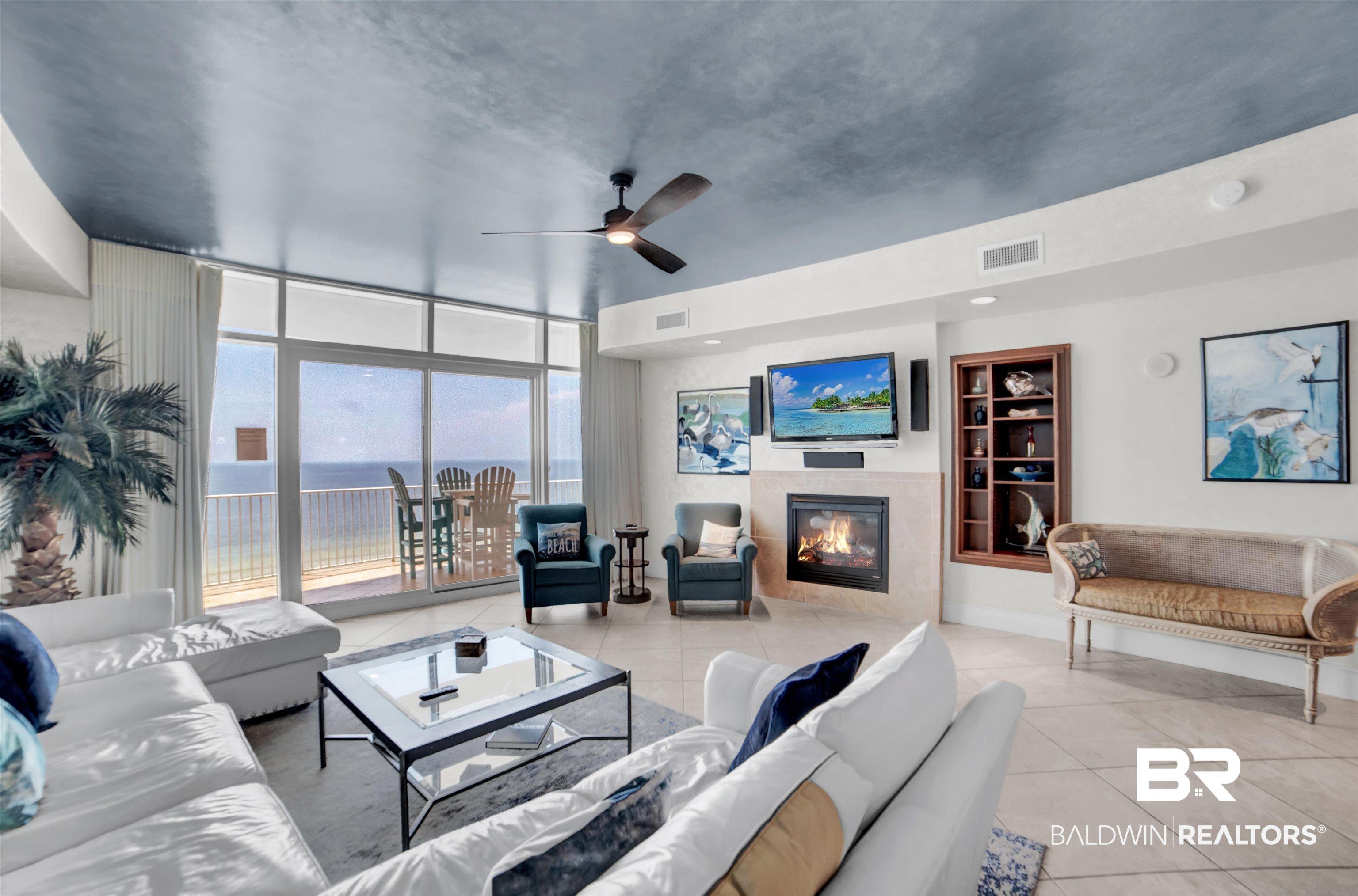 Image 4: Living room with a wall of windows, light tile patterned floors, a ceiling fan, and a fireplace